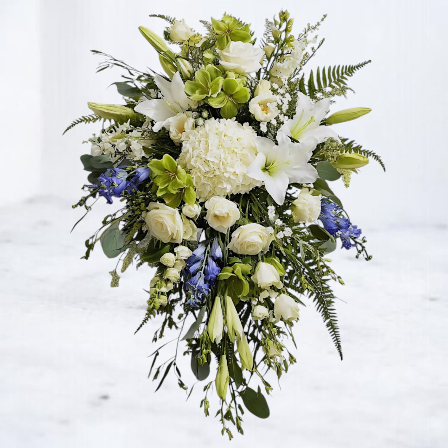 Serenity Standing Funeral Spray Serenity Standing Funeral Spray - The Serenity Standing Spray is a graceful expression of peace and remembrance. Featuring elegant white lilies, ivory roses, lush hydrangea, green and soft blue accents, this cascading spray symbolizes comfort, renewal, and everlasting love. Designed with lush greenery for depth and movement, it is a meaningful choice for funerals, memorials, or graveside services. Available for same-day sympathy flower delivery in Houston and surrounding areas, the Serenity Standing Spray provides a heartfelt tribute when words alone are not enough.