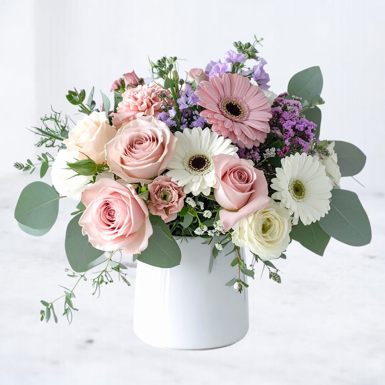 Petal Harmony Petal Harmony - Celebrate their special day with a burst of soft elegance. Our Petal Harmony Bouquet features a charming mix of pastel pink roses, creamy white gerbera daisies, blush spray roses, and seasonal blooms in lavender and lilac tones. Designed in a modern white vase, this fresh arrangement is the perfect way to say “happy birthday” with style. Handcrafted for a light, airy feel, it’s ideal for brightening any celebration—whether it’s delivered to their home, office, or party venue. Same-day birthday flower delivery available in Houston, Magnolia, The Woodlands, Spring, Conroe, Cypress, and surrounding areas. Perfect for: Birthdays, milestones, or simply to make someone smile.