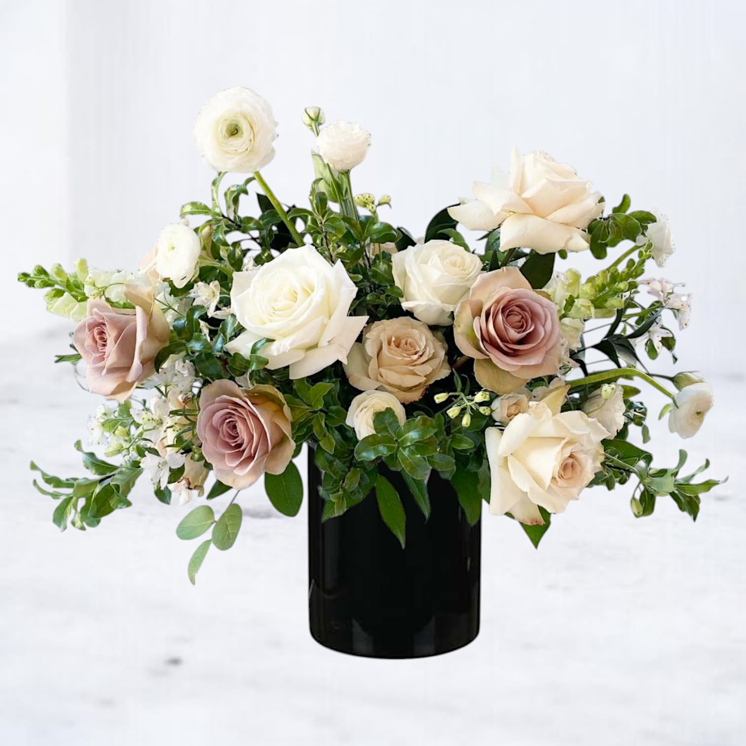 Mink Glow Mink Glow - Mink Glow is a sophisticated floral arrangement that speaks in hushed tones of elegance and romance. Featuring a graceful blend of ivory roses, soft taupe blooms, and creamy ranunculus set against rich greenery in a sleek black vase, this bouquet is the epitome of understated luxury. Perfect for celebrating birthdays, anniversaries, engagements, or simply showing your refined taste, Mink Glow offers a timeless alternative to traditional color palettes. Its neutral tones make it ideal for both modern and classic interiors—whether you're sending it as a thank-you gift, a sympathy gesture, or just because. Available for same-day flower delivery in Houston, Magnolia, The Woodlands, Conroe, and surrounding areas.