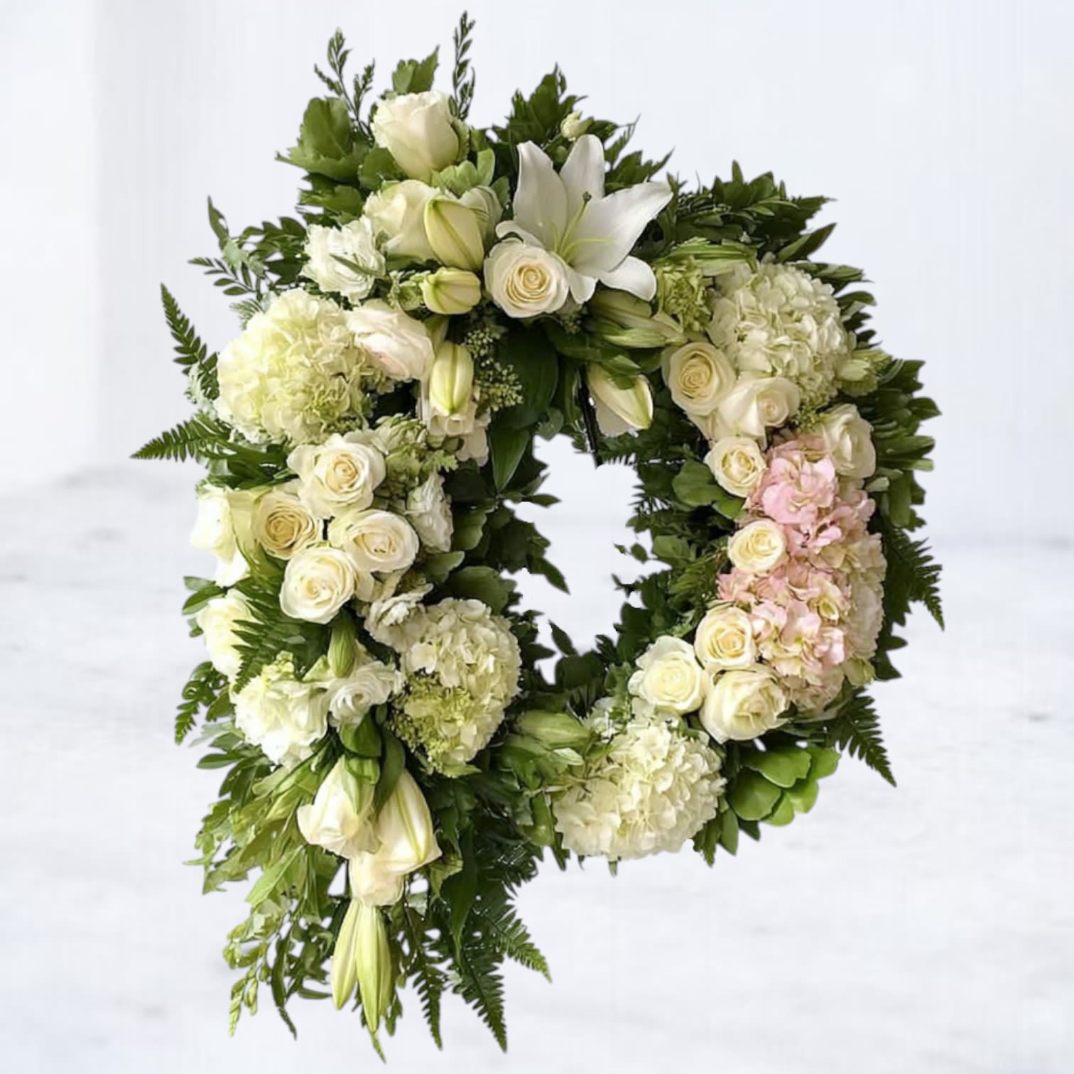 Empyrean Embrace Wreath Empyrean Embrace Wreath - Honor a life well lived with the Empyrean Embrace Wreath, a serene design crafted with white roses, hydrangeas, lilies, and soft touches of greenery. Its 24" circular form symbolizes eternity and everlasting love, while its delicate blooms bring comfort and peace to those mourning. Perfect for funeral services or memorial ceremonies, this wreath offers a graceful expression of sympathy and remembrance. Local Delivery: Available for same-day delivery across Magnolia, The Woodlands, Spring, Montgomery, and surrounding Houston areas. Easel included