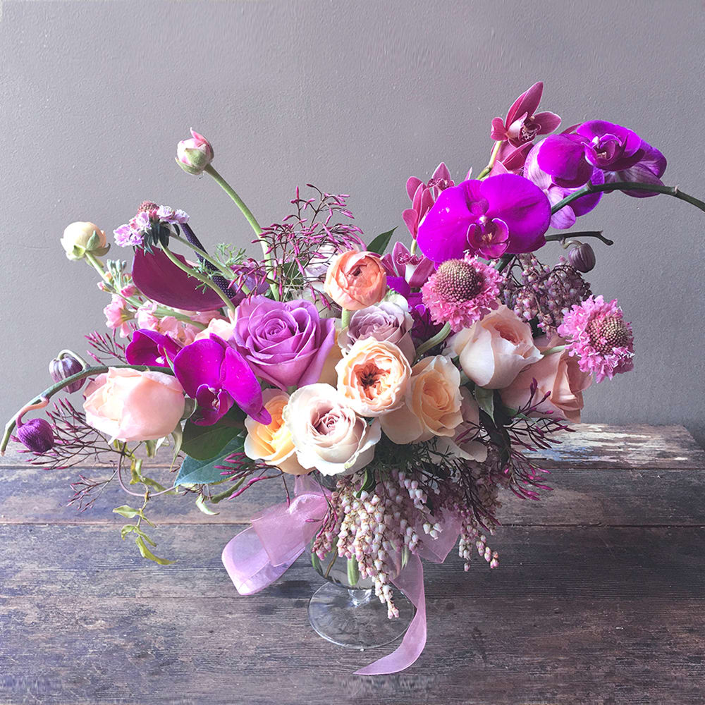 Makena (Gallery Photo) - A striking, asymmetrical floral design with roses and orchids! As artful expression of modern aesthetics, this floral beauty will surely delight any creative spirit! 