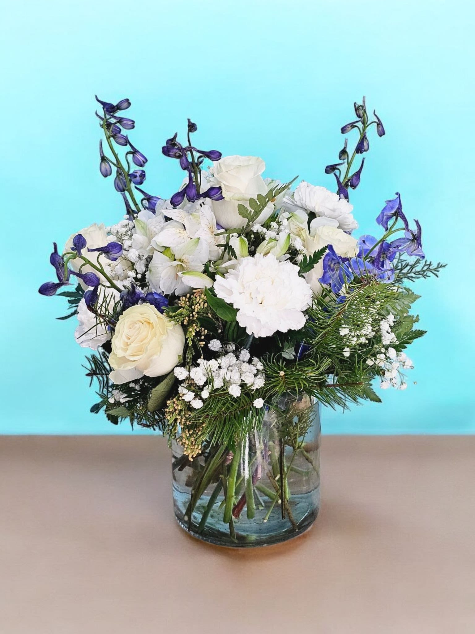 Ethereal Elegance - Indulge in pure elegance with our &quot;Ethereal Elegance&quot; bouquet. Adorned with delicate white roses, vibrant blue delphinium, and other hand-picked blooms, this arrangement exudes sophistication. Complete with a clear vase, it's the perfect gift for any occasion. Order now and experience the ethereal beauty for yourself.