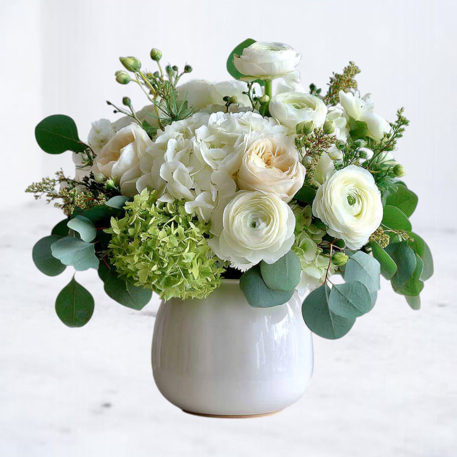 Porcelain Petals Bouquet Porcelain Petals Bouquet - Experience timeless elegance with our Porcelain Petals Bouquet, a graceful blend of creamy roses, white ranunculus, lush hydrangeas, and fresh eucalyptus. Designed in a chic white vase, this arrangement radiates sophistication and serenity, making it a thoughtful sympathy gift, a stunning centerpiece for weddings, or a luxurious everyday surprise. Available for same-day flower delivery in Magnolia, The Woodlands, Spring, and Montgomery, TX.