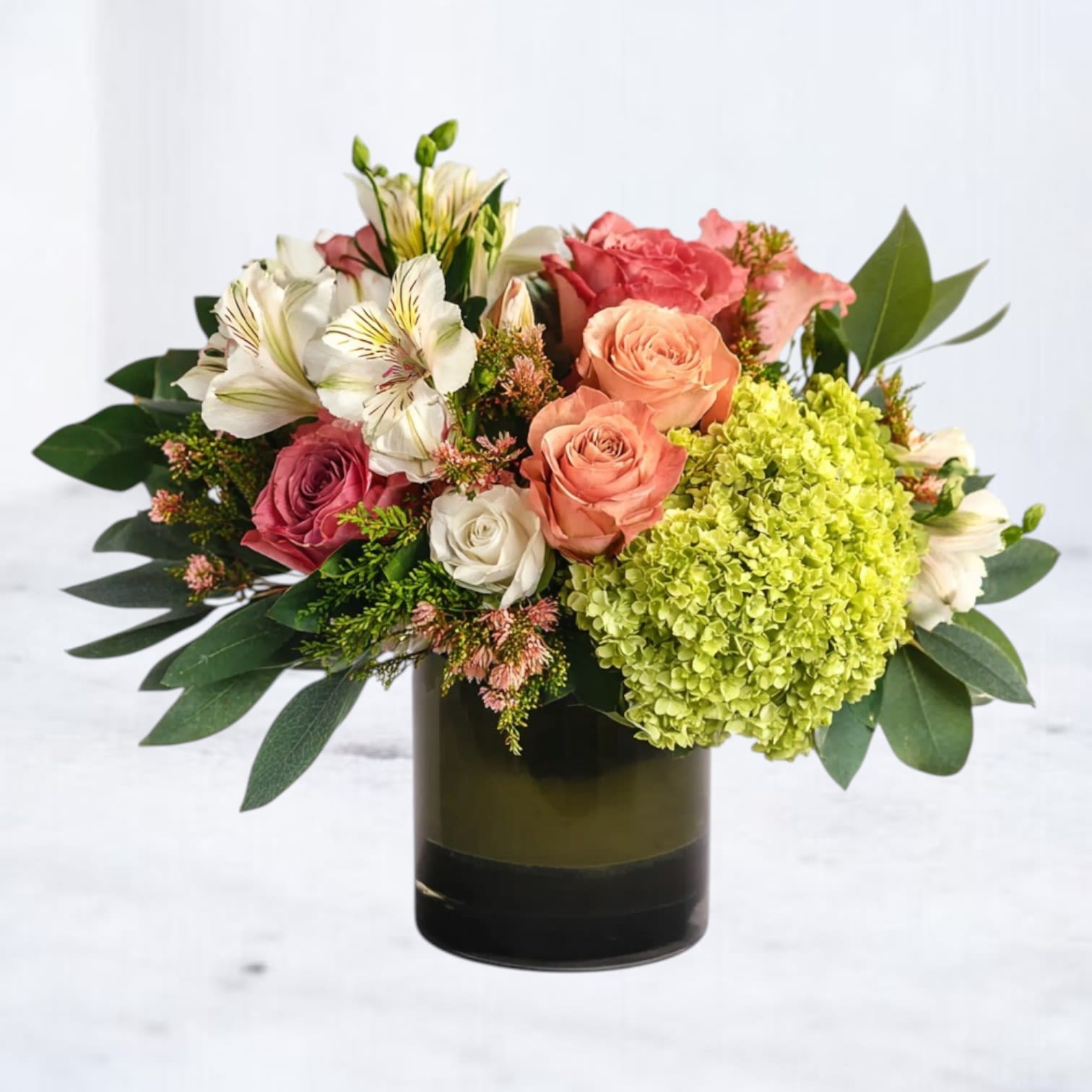 Opal Meadow Opal Meadow - Breathe in the serene beauty of Opal Meadow, a graceful floral arrangement that blends modern elegance with organic charm. Bursting with vibrant peach and coral roses, lush green hydrangea, soft ivory alstroemeria, and seasonal accent blooms, this arrangement is designed in a sleek glass vase for a polished yet natural look. Perfect for birthdays, anniversaries, thank-you gifts, or simply brightening someone’s day, this bouquet captures the warmth of a summer garden with a modern twist. Same-day flower delivery available in Houston, Magnolia, The Woodlands, Spring, Conroe, and surrounding areas.
