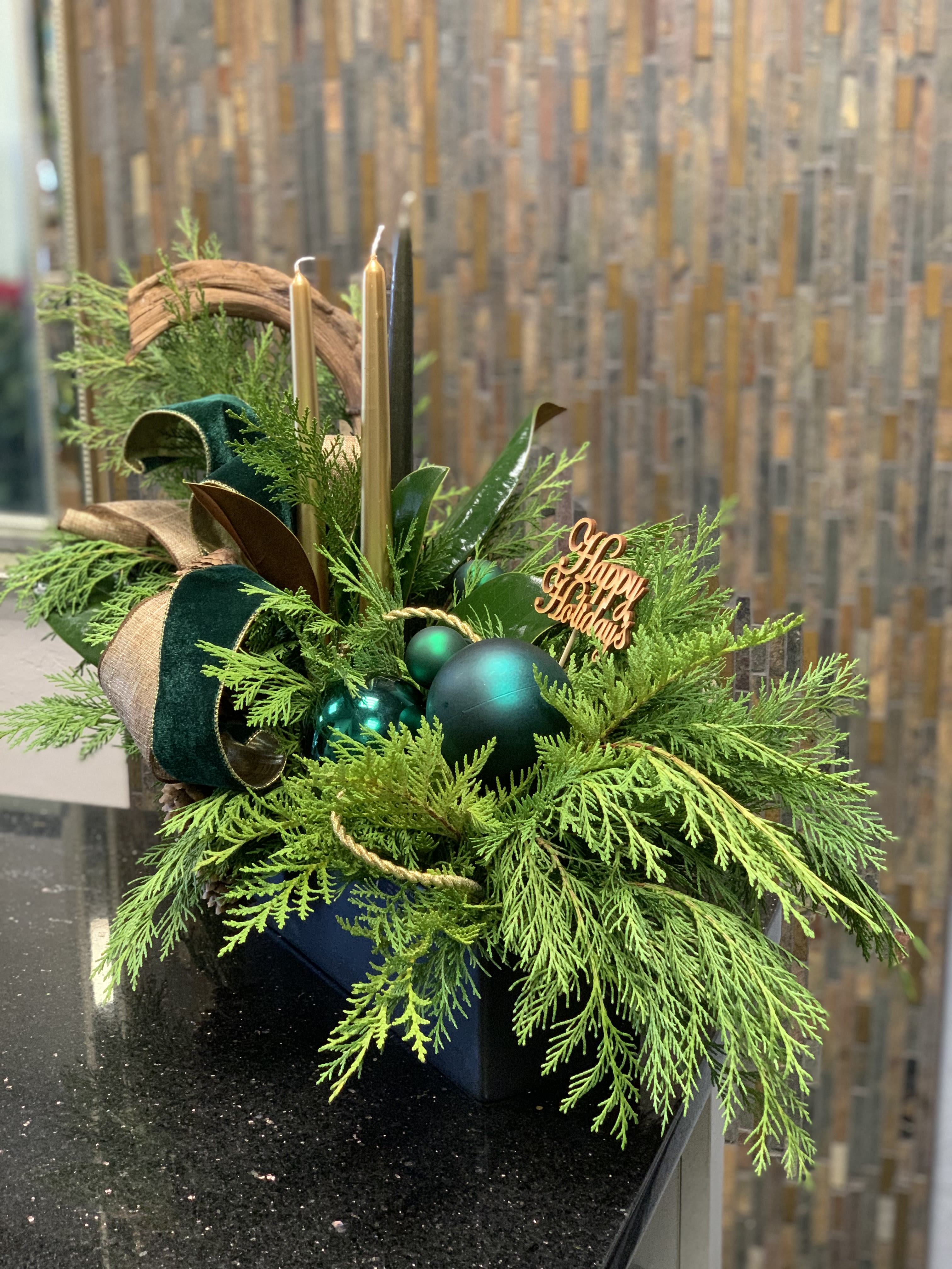 Green and Gold Holiday Centerpiece  - Our green and gold Holiday centerpiece is made of dry pine cones, fresh greenery, and a velvet ribbon bringing a touch of luxury.
