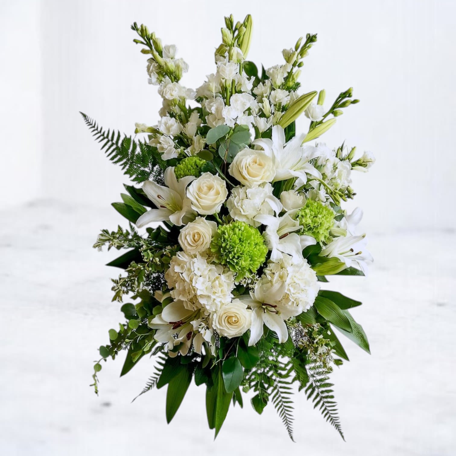 Serene Remembrance Standing Funeral Spray Serene Remembrance Standing Funeral Spray - The Serene Remembrance Standing Funeral Spray is a timeless expression of sympathy, featuring elegant white lilies, ivory roses, lush hydrangea, and soft green accents. Designed in a cascading style with fresh greenery, this arrangement symbolizes peace, comfort, and eternal love. Its soothing palette makes it a meaningful tribute for funeral services, memorials, or graveside ceremonies. Available for same-day sympathy flower delivery in Magnolia, The Woodlands, Spring, Tomball, Houston and surrounding areas, the Serene Remembrance Standing Funeral Spray offers a heartfelt way to honor and remember a loved one.