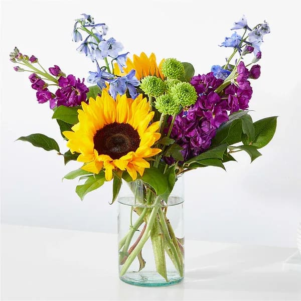 Catching Rays Bouquet - Travel to a warm summer day with the Catching Rays Bouquet, a glorious blend of yellow, blue and purple florals.  Details The Standard Bouquet is approximately 12&quot;H x 12&quot;W. Designed by florists, ready to display. For long–lasting blooms, replace the water daily. We suggest trimming the stems every couple days. Pet Safety Precautions: This bouquet or plant may include flowers and foliage that are known to be toxic to pets. To keep them safe, be sure to keep this arrangement out of your pet's reach.  Bloom Details Delphinium Stock Sunflower