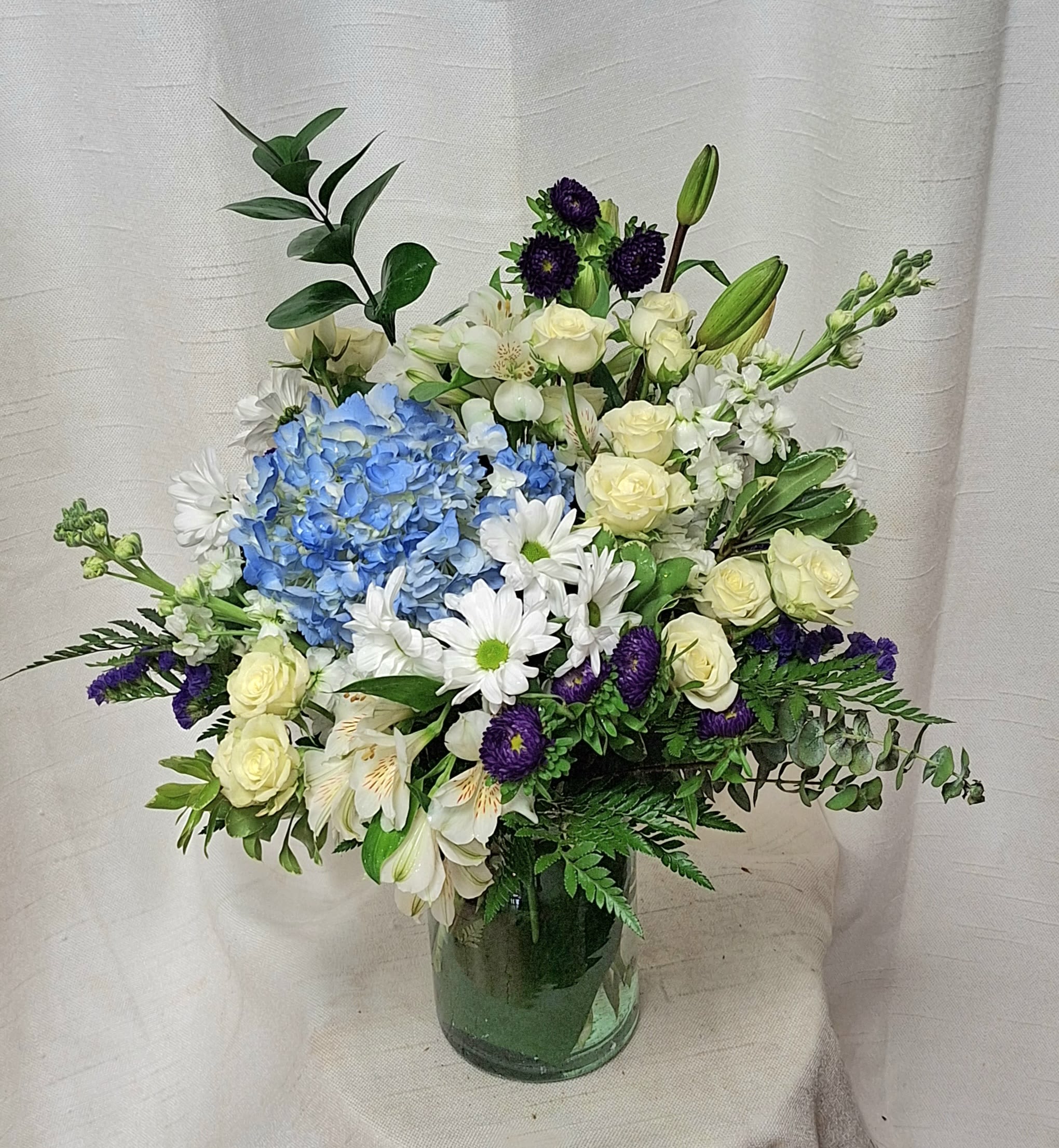 Baby Boy (BR) - Celebrate the arrival of a precious baby boy with the enchanting beauty of the &quot;Baby Boy Bliss&quot; arrangement. This delightful ensemble features a combination of blue hydrangeas, white roses, white daisies, and white alstroemerias, perfectly capturing the innocence and charm of a newborn.