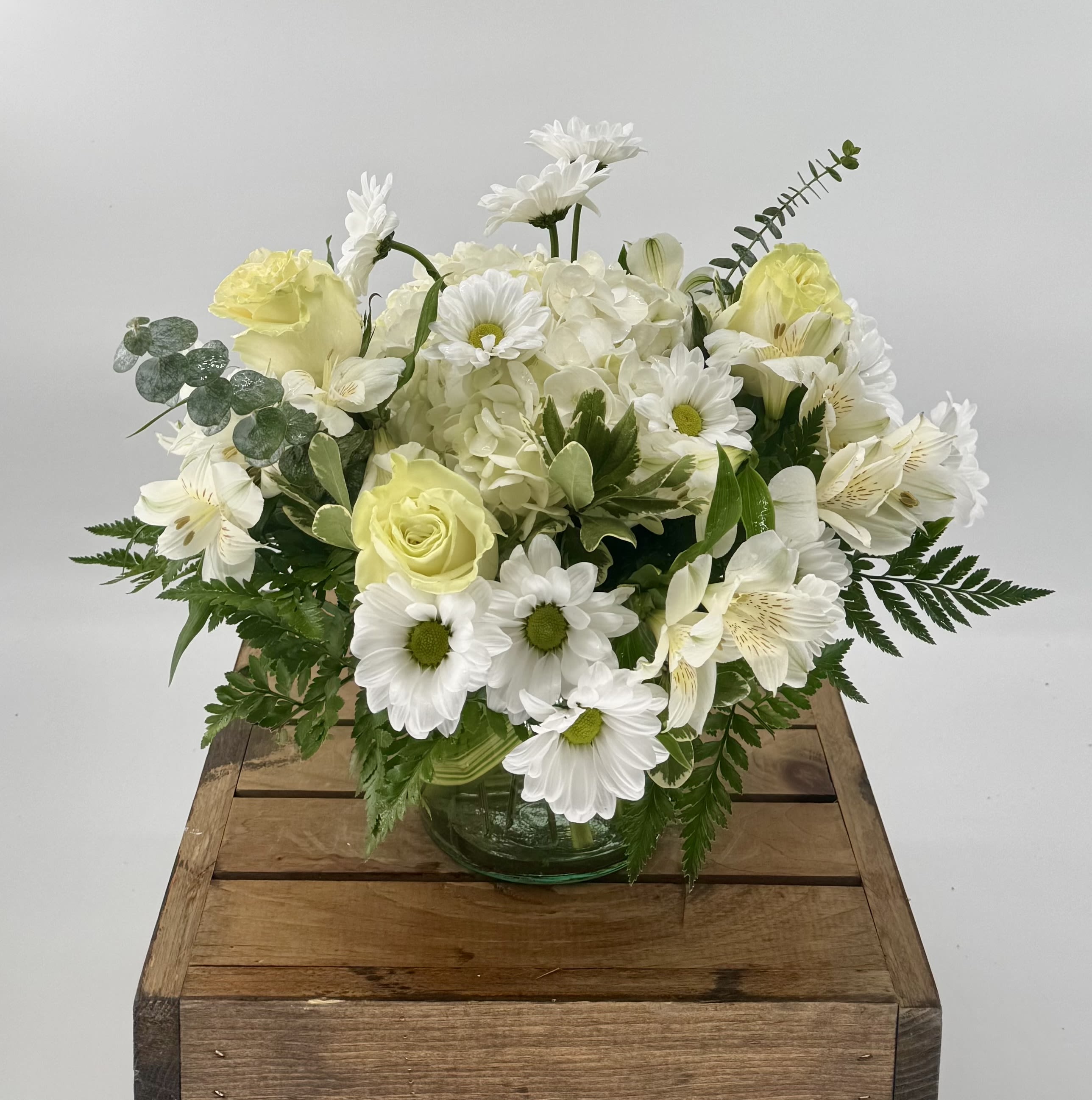 White Wonderland (BR) - Seasonal white flowers arranged in a leaf lined glass vase. Perfect for the home or office!  A monochromatic scheme with premium flowers such as roses, hydrangea, alstroemeria, and the finest greenery.