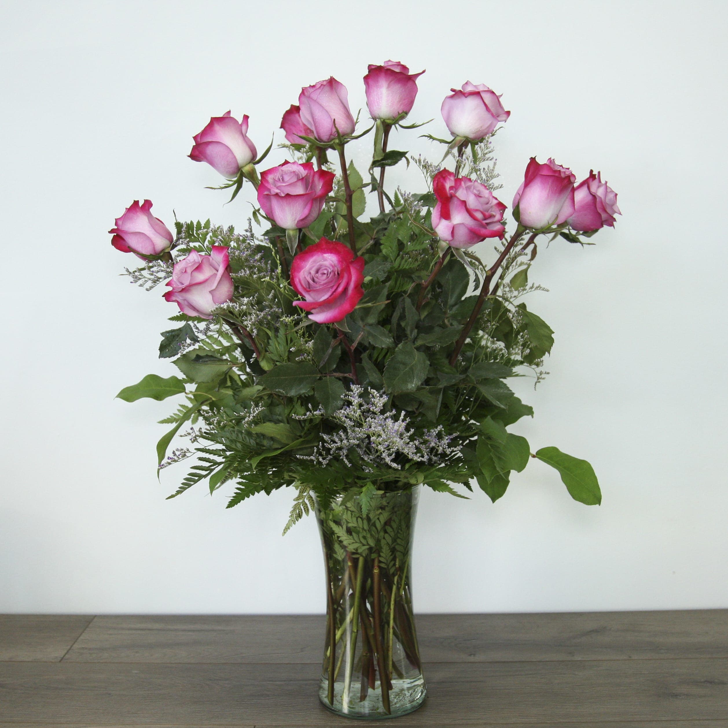 Classic Purple Roses (EXP 21) Classic Purple Roses (EXP 21) - The classic rose arrangement for any occasion, these bright lavender roses with dark purple edges are guaranteed to brighten anyone's day. The arrangement is completed with fresh greenery for added dimension and color. Placed inside a glass vase.