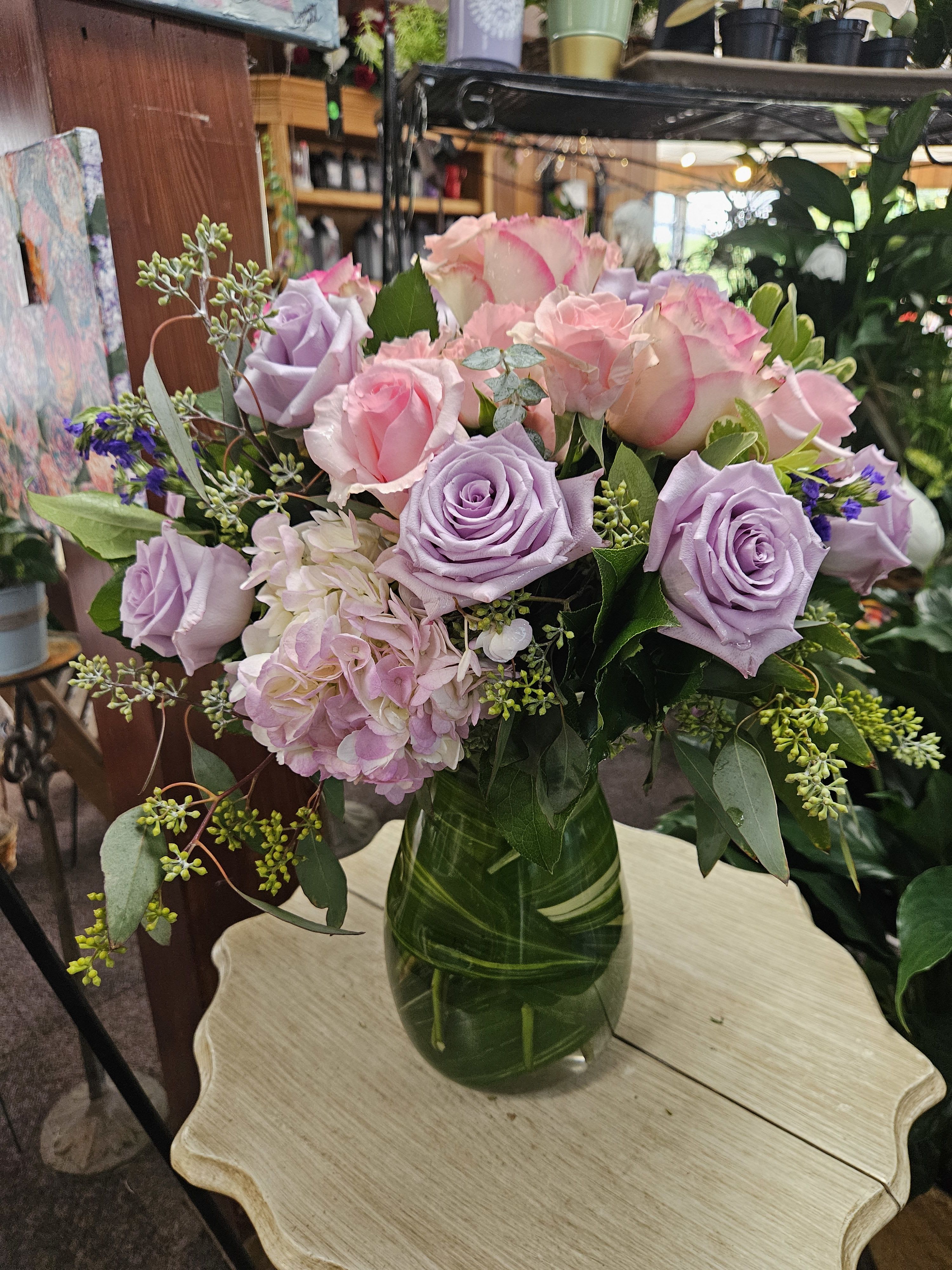 Your Light Shines - This softly elegant gesture of condolence and affection honoring the memory of a life well lived is a gentle touch during a difficult time. Lavender and pink flowers such as roses, hydrangea, statice, eucalyptus, and salal are arranged in a clear glass Jordan vase.