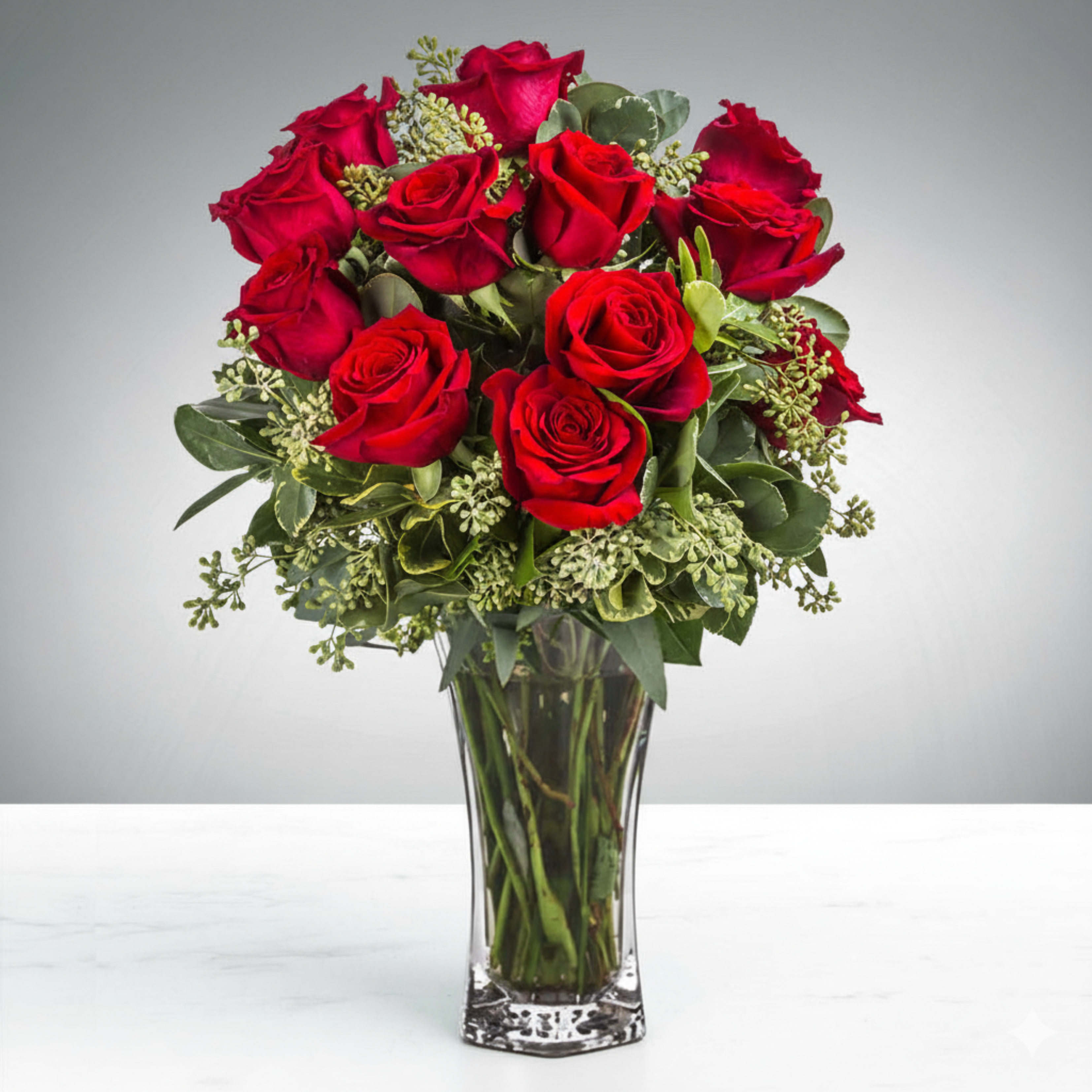 Enduring Grace - It begins with resolve—the kind forged in vows spoken once but honored through countless hours since. This is not routine, but remembrance and renewal made visible. A choice meant to say: I see you. I still choose you.  An anniversary demands a tribute that mirrors who she is: steadfast in devotion, elegant in spirit, and constant through every season. Where language falters, these blooms step forward to speak with certainty.  This is Enduring Grace. Here, crimson blooms burn with a quiet passion, vivid and unwavering. Eucalyptus lends refinement—a grace that endures—while pittosporum steadies the whole, echoing the strength of a love that has weathered both ease and storm. Each element is a reflection; facets of her, woven into form.  Placed before her, she recognizes herself in its beauty. Honored, cherished, and celebrated not just for the years past, but for every season yet to come. Every bloom tells a story.  Perfect for Naples anniversary flowers, meaningful romantic gifts, and symbolic crimson floral arrangements.  Designer's Tip: Telling a Story with Flowers For a truly personal anniversary gift, choose blooms that reflect your story. The passion of crimson, the refinement of eucalyptus, and the strength of rich greens combine to create a meaningful narrative of a love that has endured and grown stronger over time.  Order by 9am for next-day Southwest Florida delivery.