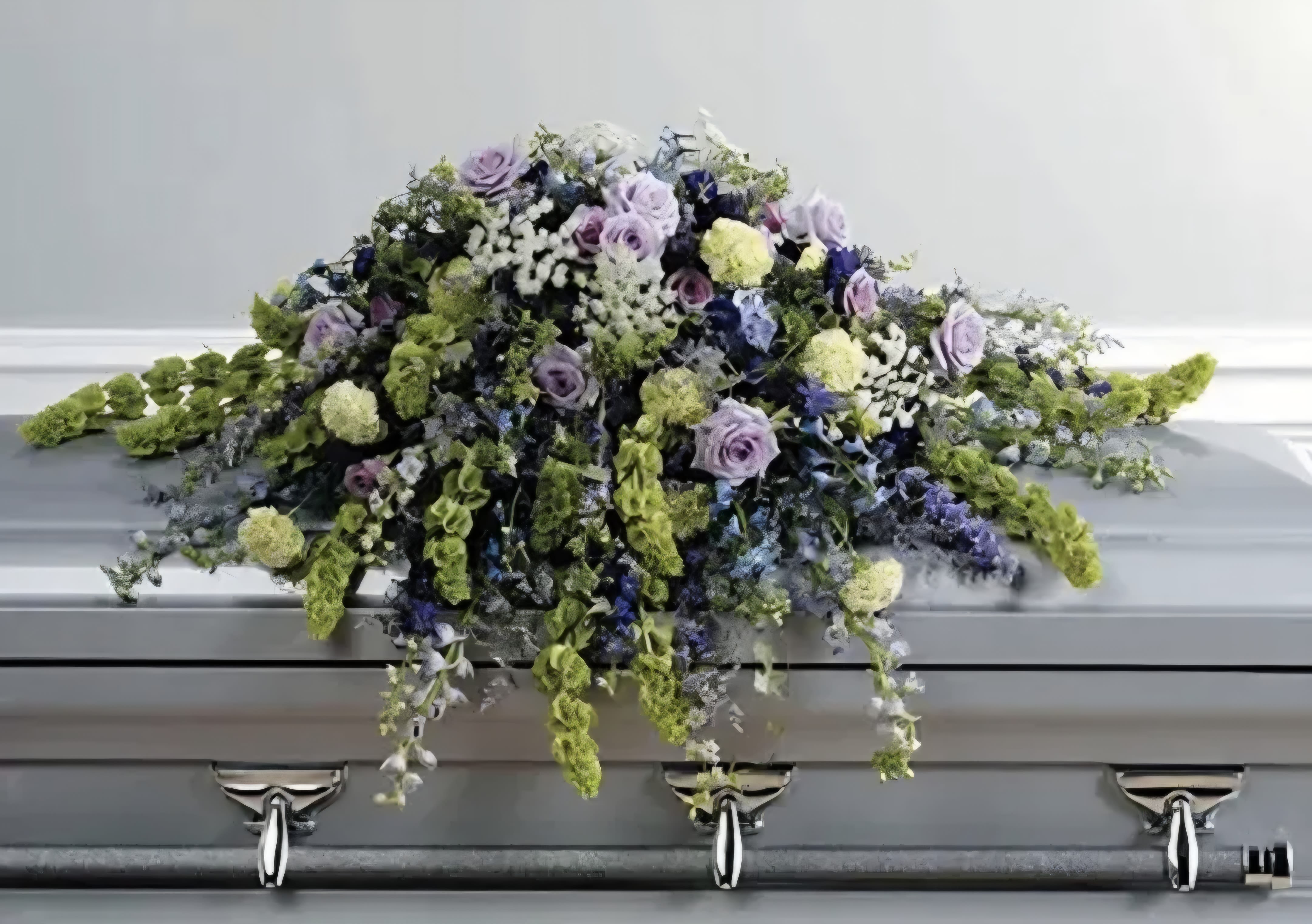 Peaceful Passage - This casket spray features blues, greens and purples. It shows bells of ireland, roses and delphinium and much more for you loved one.