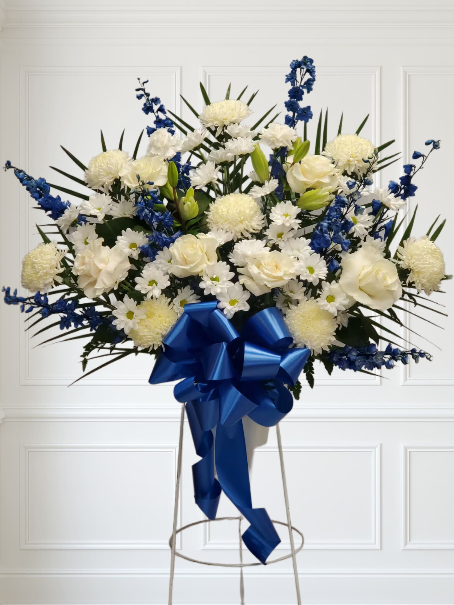 Blue and White standing basket Blue and White standing basket - This Blue and White standing basket includes, 8 white mums, 8 blue delphinium, 8 white daisy, 2 white carnations and 8 white lilys.