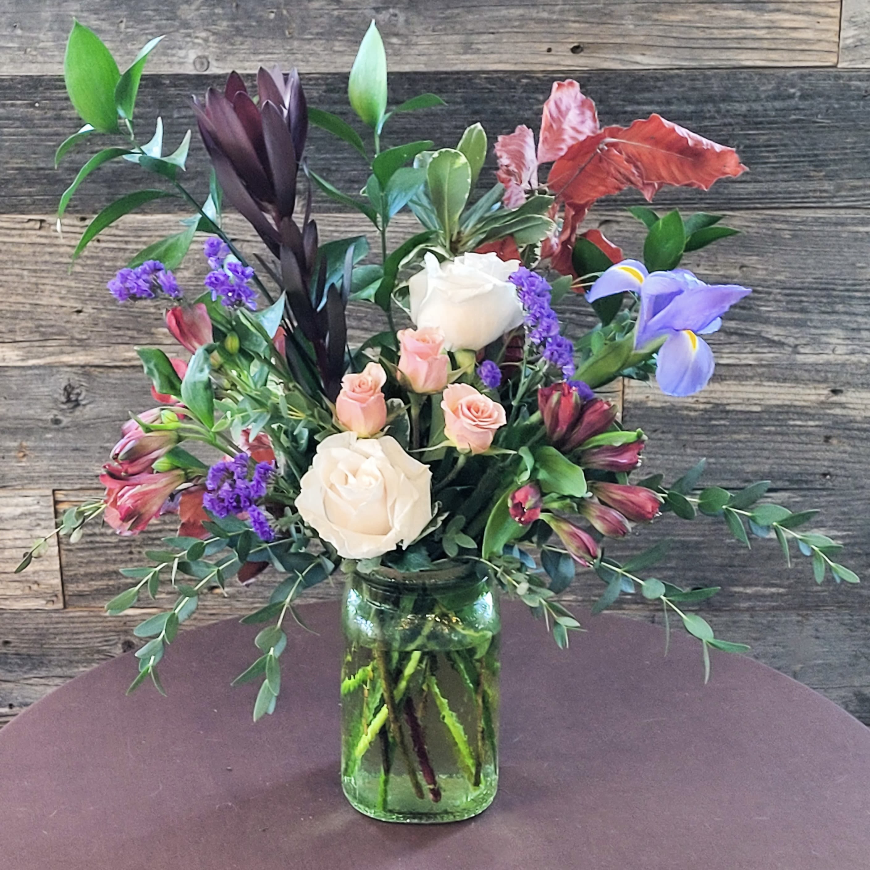 Wild Radiance - A dynamic arrangement of roses, tropical blooms, and lush greenery. 