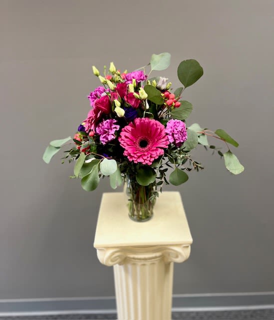 Just Because - Bright pink, lavender, and purple flowers gathered in a glass vase. 