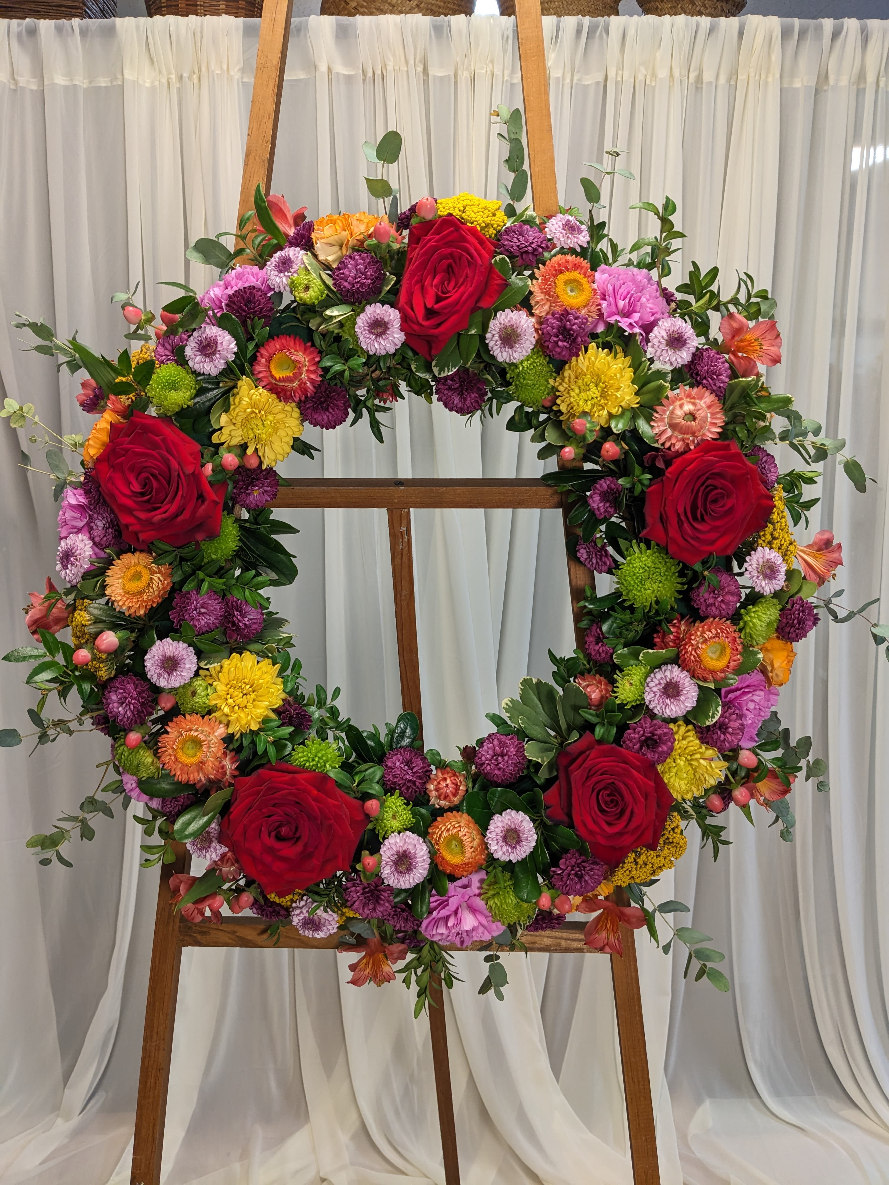 Loving Thoughts Wreath Loving Thoughts Wreath - A standing wreath fresh flowers in yellow, pink, red and orange with greenery will send a message of harmony, helping to celebrate a meaningful life.