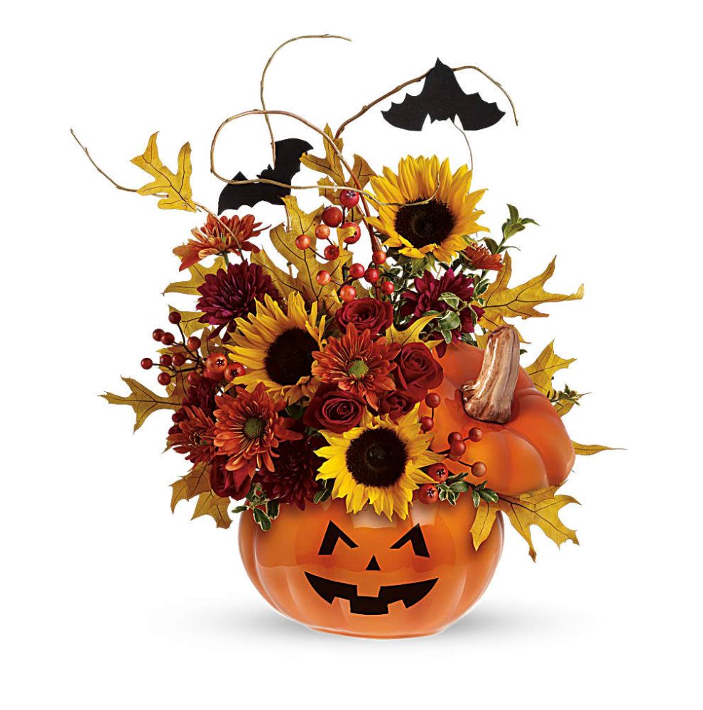Trick &amp; Treat Bouquet - This is one impressive boo-quet! Red spray roses and bright yellow sunflowers are accented by curly willow and festive black bats. Situated inside the ceramic Trick &amp; Treat Pumpkin and adorned by a scary jack-o-lantern face, this arrangement is fang-tastic! Red spray roses and yellow sunflowers are accented by orange daisy spray chrysanthemums, burgundy cushion spray chrysanthemums, curly willow, orange berries and yellow oak leaves. Delivered in a ceramic pumpkin. Orientation: One-Sided