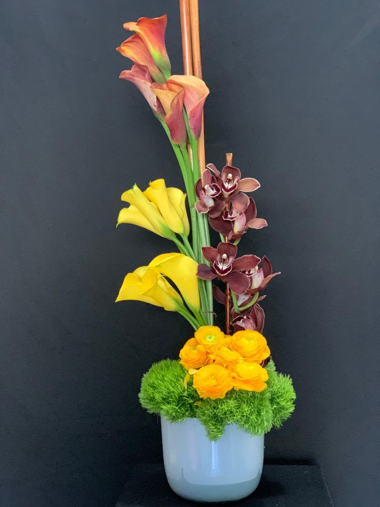 Calla Lillies, Ranunculus &amp; Cymbidium Floral Arrangement - Elegant floral arrangement featuring callas, ranunculus, and cymbidium orchids. A stunning blend of sophistication and beauty, perfect for any occasion.  Please note, flowers may be substituted based on availability. Order this exquisite arrangement today!