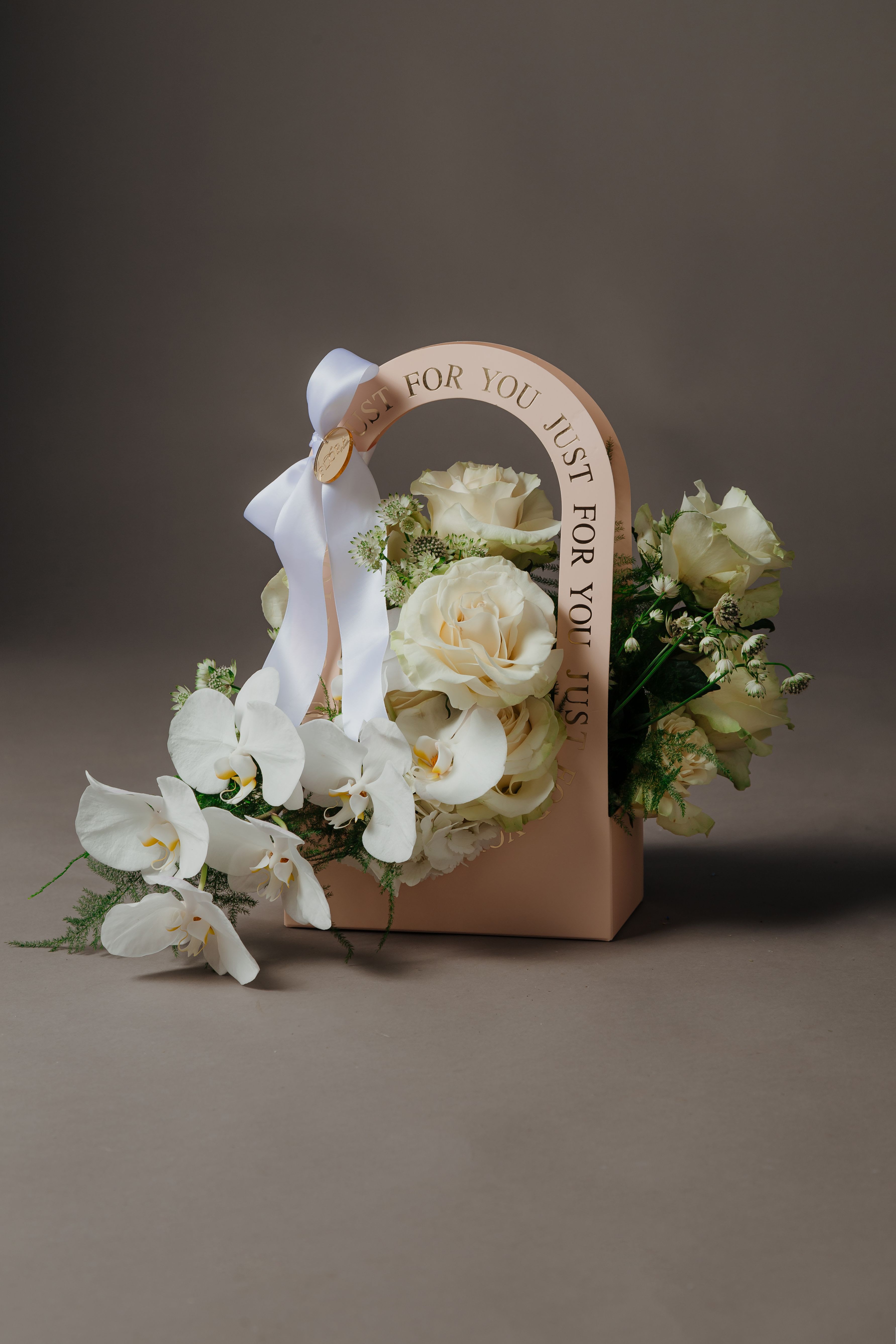 Just for You White Carry-On Flowers Arrangement  - Surprise mom with the delicate beauty of the &quot;Just for you White Carry-on Arrangement&quot; from Flora by Cortez. This petite arrangement is designed to convey your love and appreciation in a charming and compact package.  Featuring pristine white blooms and lush greenery, this arrangement exudes elegance and grace, making it the perfect gift for Mother's Day. Whether displayed on a bedside table, kitchen counter, or office desk, the &quot;Just for you White Carry-on Arrangement&quot; adds a touch of freshness and warmth to any space.  Presented in a quaint carry box, this arrangement is easy to transport and can be conveniently placed wherever mom desires. Its small size makes it ideal for expressing your sentiments in a subtle yet meaningful way, ensuring that your gesture is both heartfelt and memorable.  Show mom how much she means to you with the understated beauty of the &quot;Just for you White Carry-on Arrangement.&quot; Let this exquisite arrangement be a symbol of your love and gratitude on her special day.