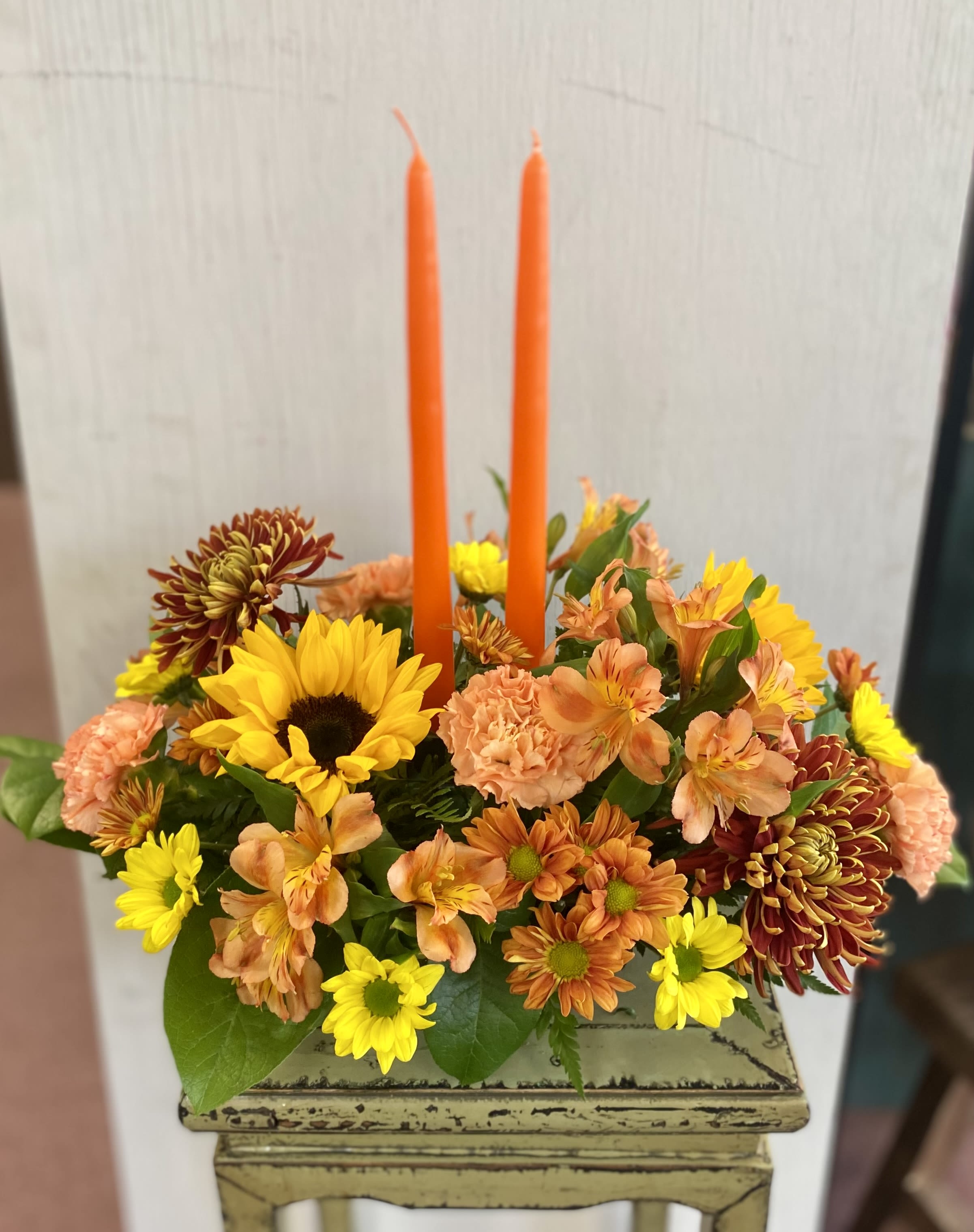 Elegance Autumn Centerpiece Elegance Autumn Centerpiece - Warm the holiday table with this beautiful centerpiece in striking autumn colors. A mix of long lasting premium blooms, natural elements, and two taper candles to provide a lovely glow.