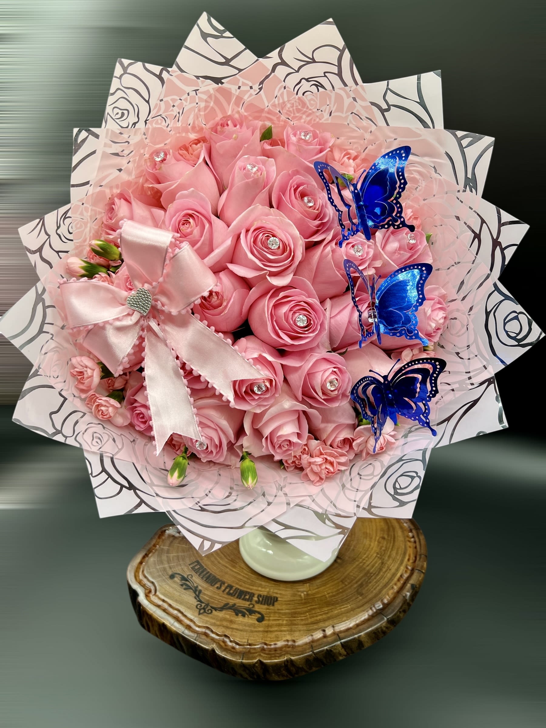 Just a Reminder I Love You - A touch of magic and elegance in every petal  This enchanting bouquet of soft pink roses sparkles with crystal accents and is brought to life by vibrant blue butterflies, symbolizing transformation and beauty. Wrapped in delicate floral paper and finished with a satin heart bow, it’s a dreamy gift for someone truly special.  25 Roses can be any Color.