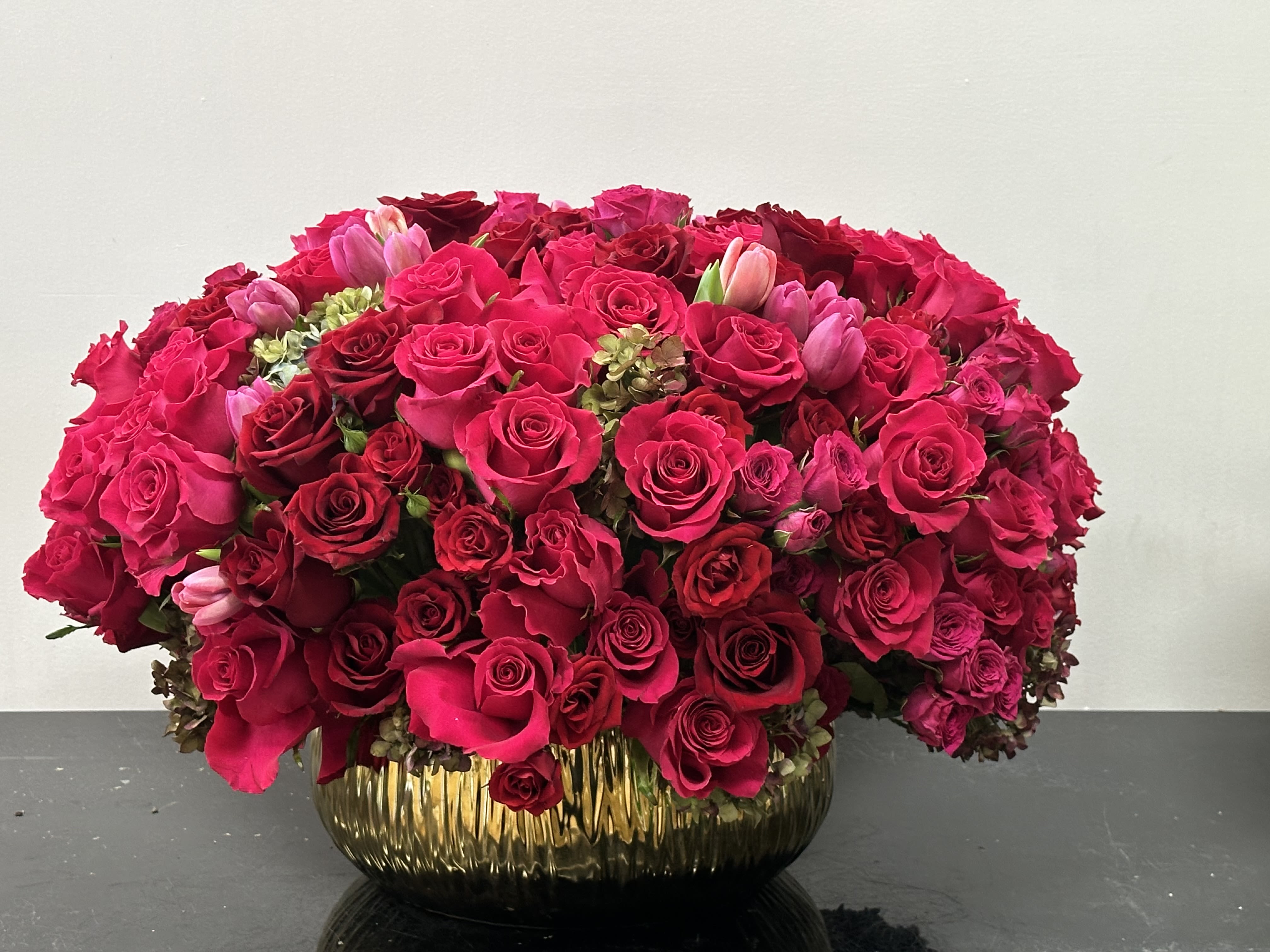 Love Roses - A love affair of Fushia and red roses infusing a melody of love and romance. A vibrant lush composition resting in gold vase for a luxurious style. With the deep bright pallet of rose brings dimensional style sure to brighten any space.      Some florals are seasonal, if particular flower will not be available due to season, we will substitute for similar flower, composition, color pallet and value of the arrangements as closely as possible. All effort to create a floral arrangement as close to the photo shown, the actual arrangement may vary slightly in its appearance from the photo shown. If you have any questions about your order, we welcome you to call us in or email