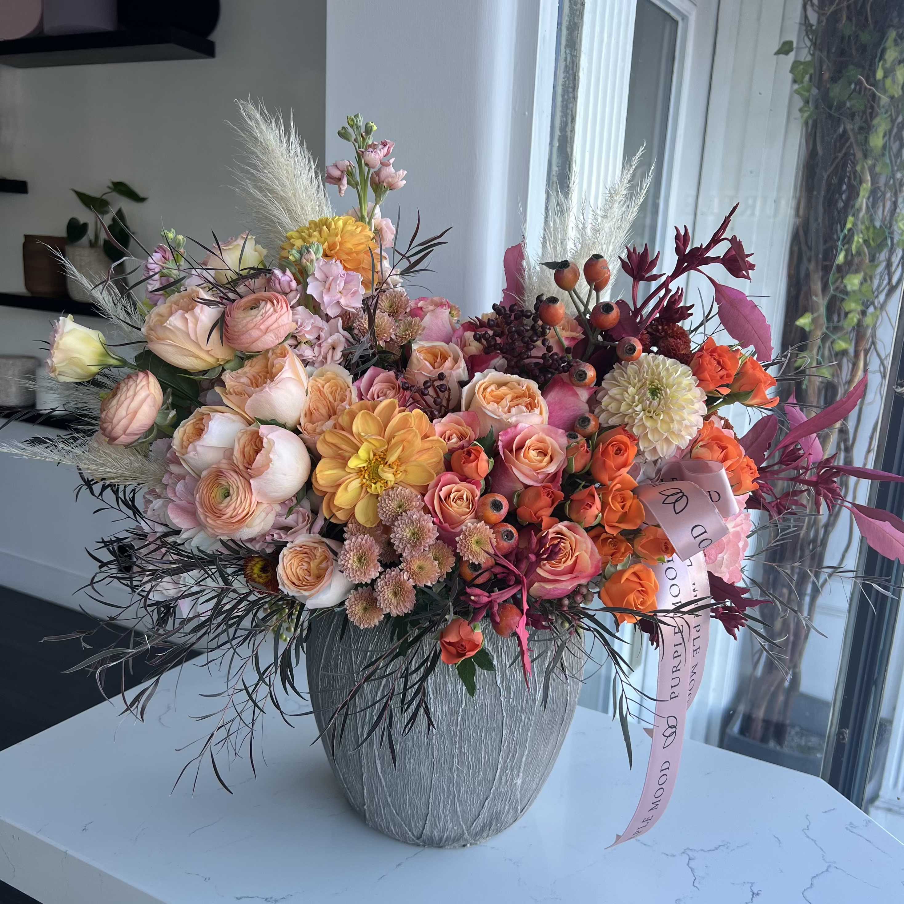 Vase with Warm Thanks - This beautiful centerpiece is crafted with a blend of autumnal blooms, including roses, dahlias, and seasonal textures, all in warm, inviting hues. Perfect for sharing the spirit of Thanksgiving, this arrangement brings a touch of elegance and warmth to any table, making it an ideal gift or decoration for gatherings. Let ‘With Warm Thanks’ convey your appreciation in the most vibrant way.