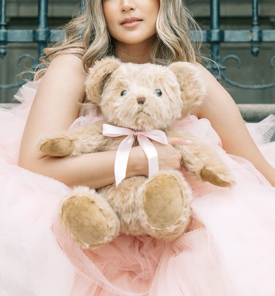Monsieur Pièrre - “Bonjour, mon ami! I am Monsieur Pièrre — a charming little bear with Paris in my soul, a heart as soft as my fur, and arms ready to give you the perfect hug.  Thoughtfully crafted to be more than a teddy - I am a gentle friend, a keeper of secrets, and a timeless companion for big and little hearts alike. Adorn me on a shelf, snuggle me at bedtime, dress me in keepsake baby clothes, or take me along on everyday adventures. Mon amour, I adore exploring the world — especially with you by my side!”  The Pièrre Bear is an heirloom artist teddy bear with a touch of playful elegance - a designer keepsake, meant to be cherished for generations to come. Gift him with a bouquet of flowers to your loved one, dress him in your child’s first garments, place him on a shelf, or include him during tea time - he is waiting to join you for cuddles and can’t wait to hold your most cherished memories!   The perfect, loveable gift. This collector's item is designed with fine details including a soft pink satin/silk bow, a gold Love Barrel ®  Charm around his neck, and an embroidered applique on his paw.   