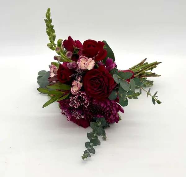 Wild Berry Nosegay - Enchanted look with a variety of fresh red, burgundy, and violet florals. When ordering please specify your choice of satin ribbon color under special instructions or it will be wrapped in a corresponding color. Designers may need to implement substitutions, however will follow the general arrangement style and color theme. Standard price point is pictured.