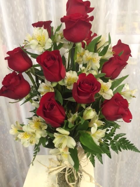 All About Love!!! - Love that has lasted forever deserves this beautiful arrangement of a dozen red roses partnered with white alstromeria nestled on a bed of green fern or other seasonal greenery. 