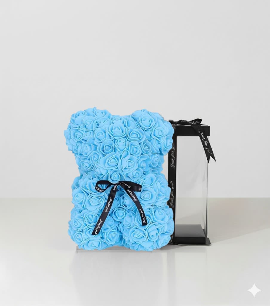 Baby Blue Rose Bear in Transparent Gift Box Baby Blue Rose Bear in Transparent Gift Box - Celebrate love in the sweetest way with our Baby Blue Rose Bear, handcrafted from dozens of delicate foam roses to create a timeless keepsake that never fades. Presented in a clear display gift box tied with a ribbon, this romantic rose bear is the perfect gift for birthdays, anniversaries, Valentine’s Day, Mother’s Day, or just because. A symbol of elegance and affection, this luxury rose bear from Je’ La Diamond Luxe Gifts makes every occasion unforgettable.