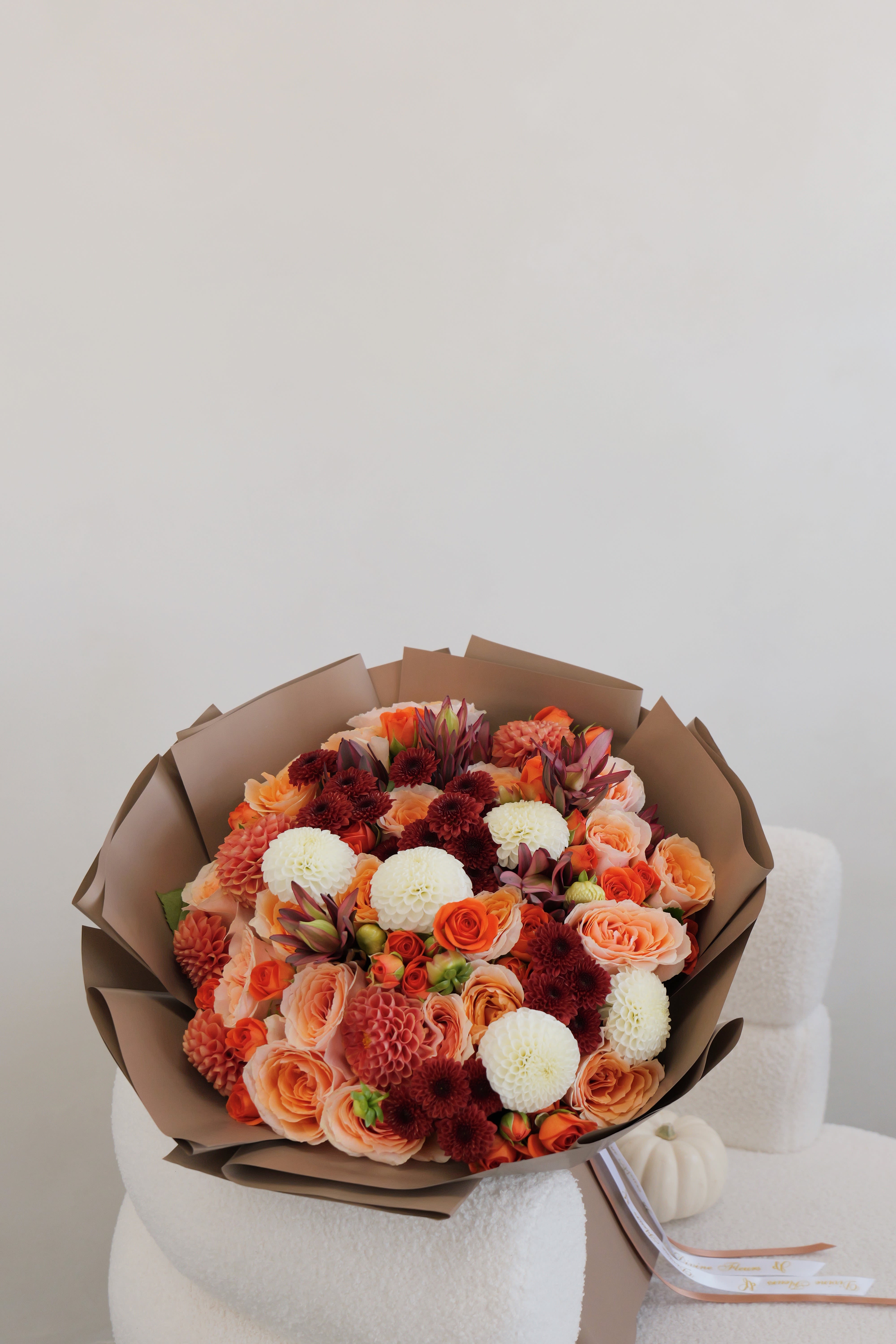 Autumn Breeze - A harmonious mix of warm orange, cream, and burgundy-colored blooms creates a bouquet full of warmth and autumn charm. Perfect for any occasion, it brings together vibrant colors and soft textures to capture the essence of timeless beauty.