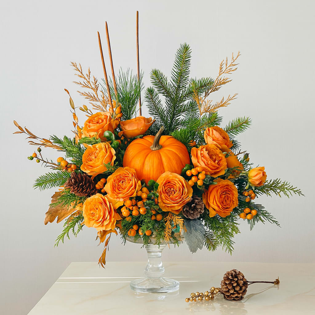 Rustic Pumpkin  - Bring the warmth of fall into your home with Rustic Pumpkin – a charming mix of orange roses, fresh greenery, pinecones, berries, and a festive mini pumpkin centerpiece. Perfect for Thanksgiving tables or as a seasonal gift.