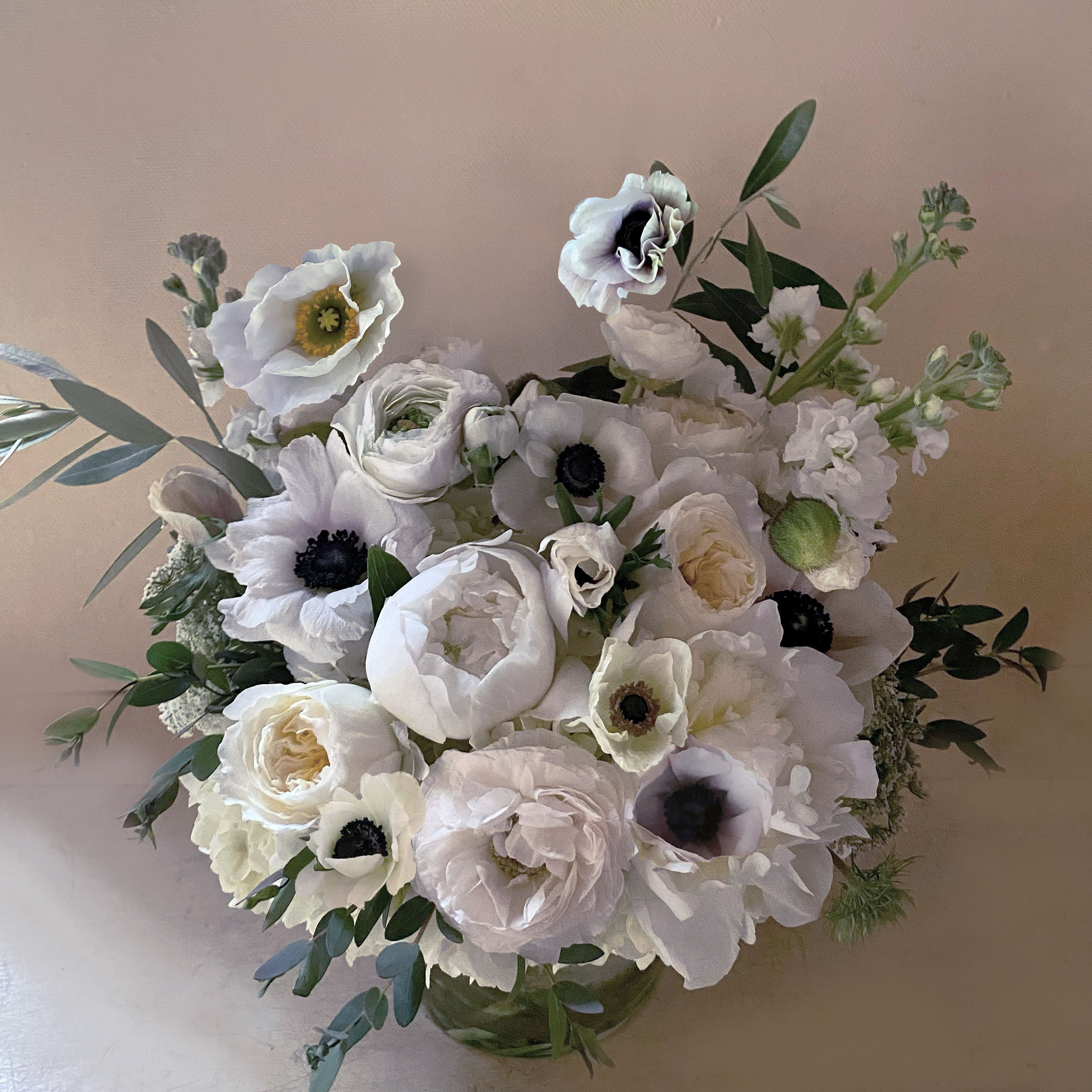 Coco - Casual chic just like Gabrielle Bonheur Coco Chanel. Her namesake arrangement of only white stems with black accents. So stylish and clean, luxurious yet natural. Perfect gift for the beauty who recieves it. Arranged in a clear cyllinder vase padded with olive branches.