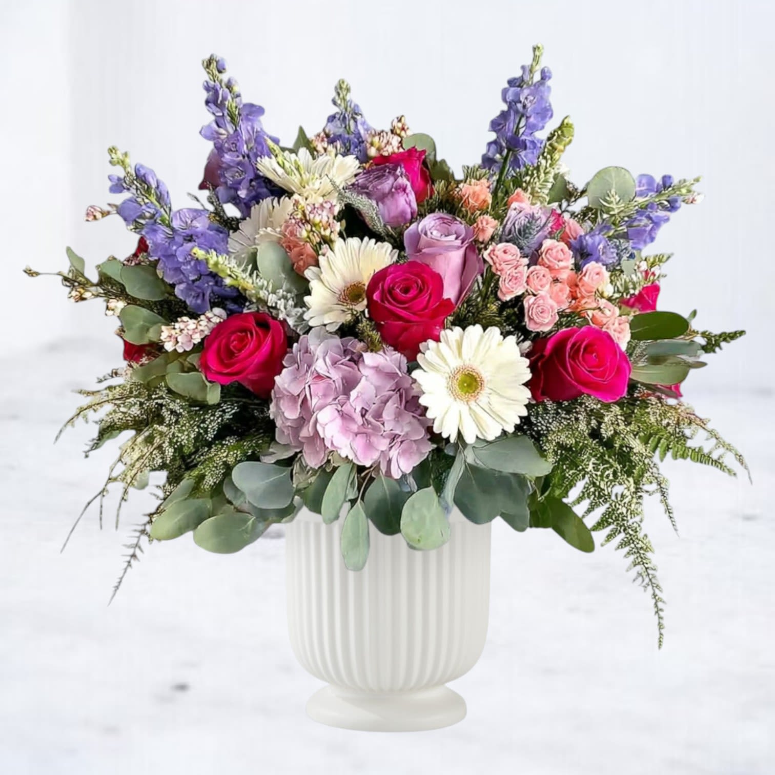 Sonata Tribute Sonata Tribute - Sonata Tribute is a breathtaking arrangement designed to uplift the spirit and bring beauty to any space. Featuring a lush mix of roses, hydrangea, gerbera daisies, delphinium, spray roses, and fresh greenery, this design overflows with color and life. Hand-arranged in a classic white pedestal urn, it offers both elegance and presence, making it a meaningful choice for sympathy tributes, celebrations of life, or sophisticated everyday gifting. Available for same-day flower delivery in Magnolia, The Woodlands, Conroe, Spring, Cypress, and surrounding Houston areas, this arrangement delivers comfort, joy, and beauty wherever it’s sent.