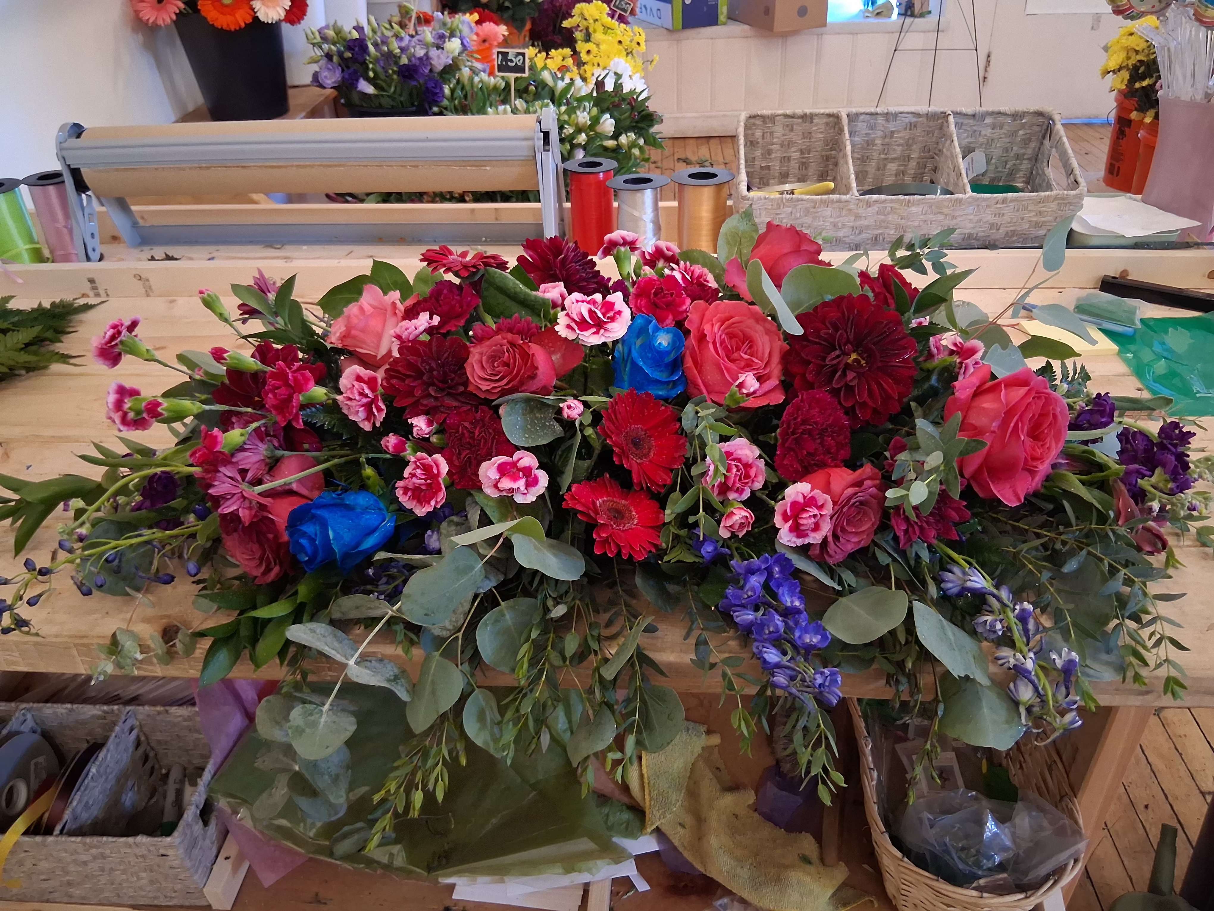 Carly wedding sweetheart table centerpiece - Bright and beautiful tones of hot pink, burgundy and dark blue with roses, delphinium, gerbera, carnations, daisies and other flowers and greens bridal table centerpiece