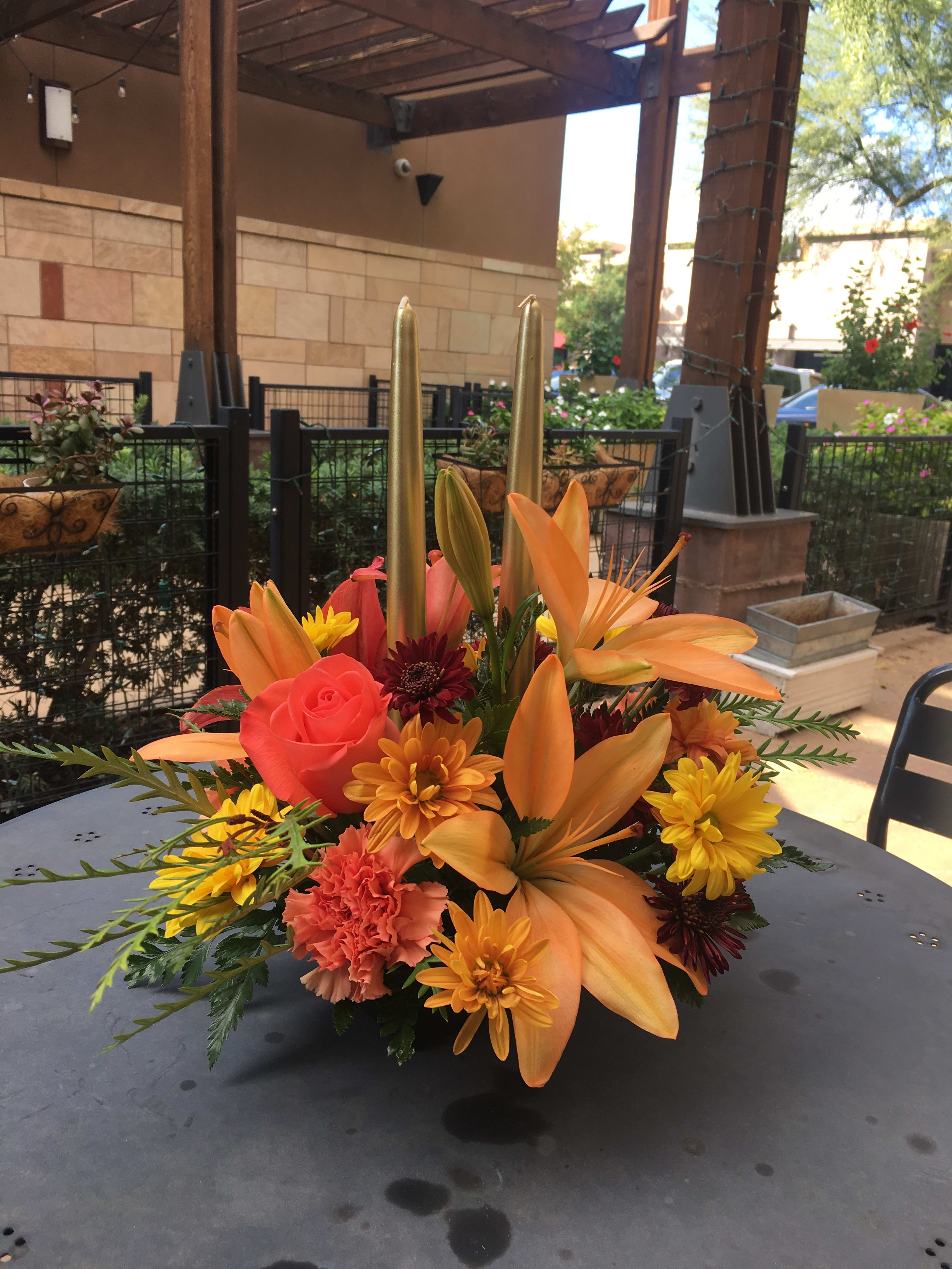 Autumn Centerpiece with Candles  - Let this stunning Floral Centerpiece grace your Thanksgiving Table or the  Table of your Loved Ones this holiday! The Grand Floral piece includes the Freshest Fall Blooms  such as Lilies, Roses, Chrysanthemums, Carnations and more. 