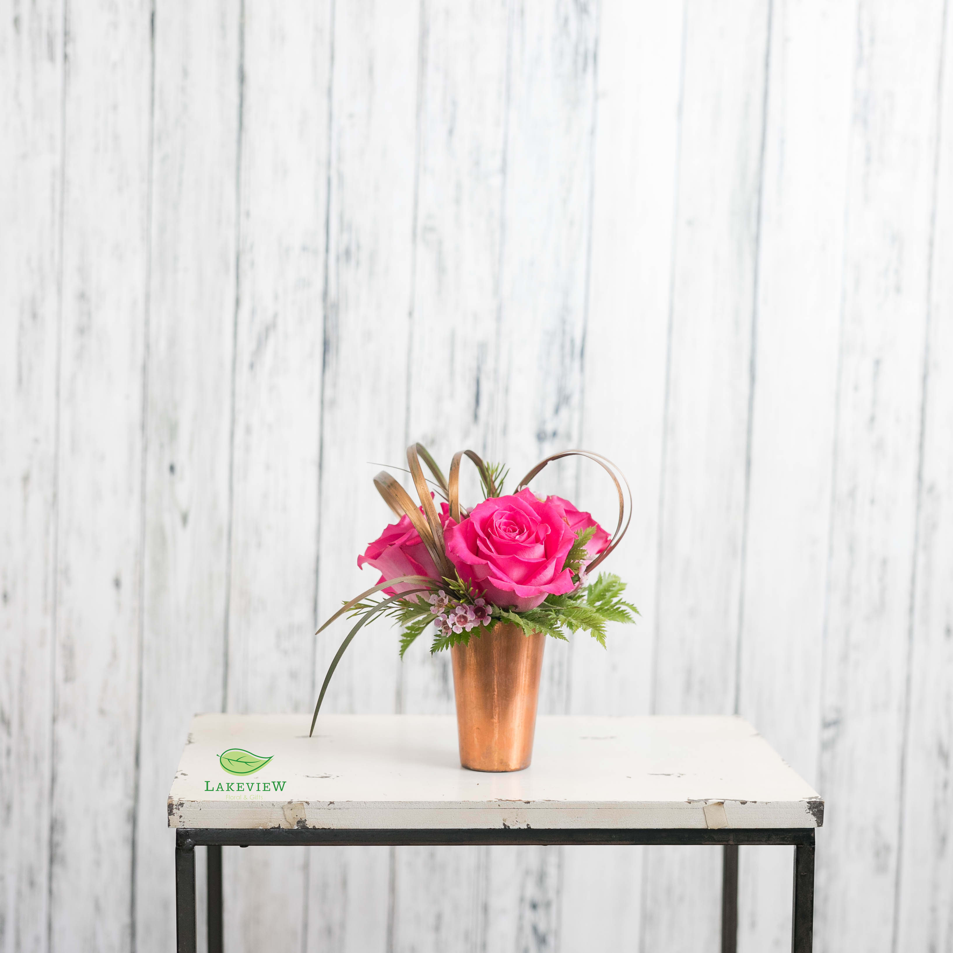 Trio Trio - Find the way to their heart with a modern collection of premium pink roses in a copper vase with golden metallic accents. A great size for a desktop, dorm or coffee table. Approx. 8"H x 6"W