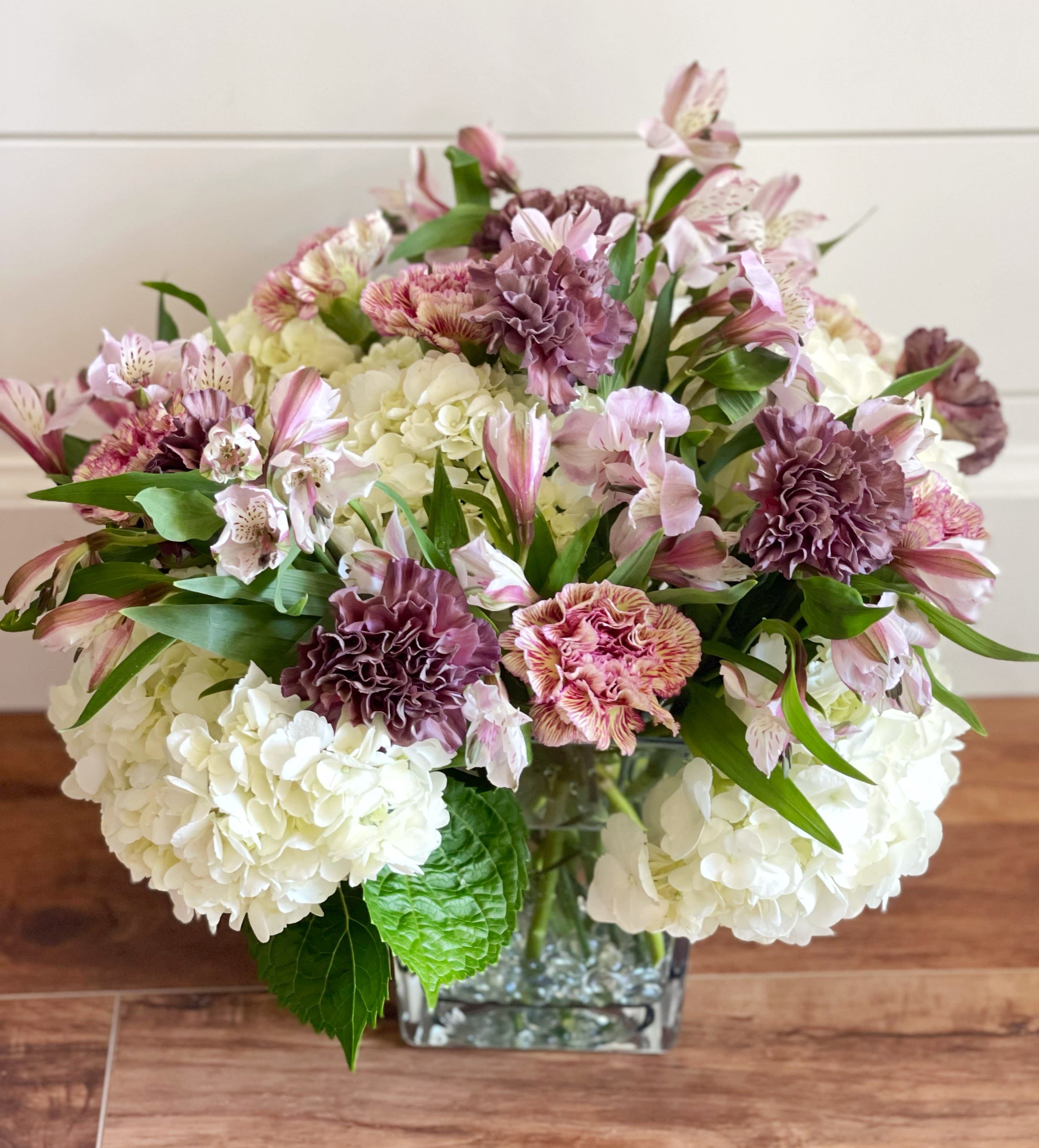 Pretty  Purples - A beautiful glass vase with white hydrangeas, alstroemerias and carnations in different purple varieties