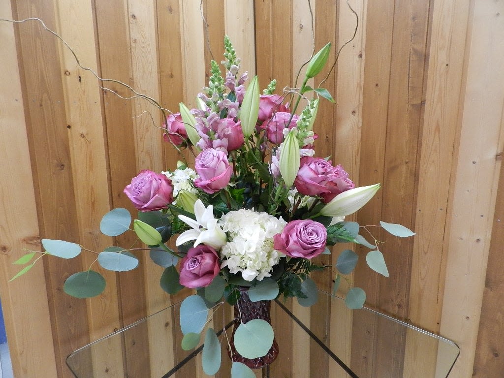 Take Me Away - Take Me Away – Fresh Flower Arrangement  Bring a touch of elegance and serenity into any space with our “Take Me Away” fresh flower arrangement from Haehn Florist and Greenhouses in Wapakoneta, Ohio. This stunning design features a stylish purple container filled with lush hydrangeas, roses, lilies, and snapdragons. Each bloom is carefully arranged to create a vibrant mix of color, texture, and fragrance that is perfect for birthdays, anniversaries, get-well wishes, or simply brightening someone’s day.  Whether you’re looking to surprise a loved one or treat yourself, this arrangement is sure to impress. Our skilled floral designers handcraft every piece with fresh, high-quality flowers to ensure lasting beauty.   Haehn Florist and Greenhouses 410 Hamilton Rd, Wapakoneta, OH 45895  419-738-8485  Order the Take Me Away flower arrangement today for local delivery or in-store pickup. Let Haehn Florist help you celebrate life’s special moments with flowers that speak from the heart.