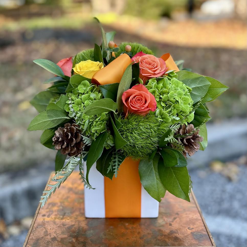 Nutmeg Nutmeg - Nutmeg | Wilmington, Delaware Florist Warm, bright, and full of seasonal charm, Nutmeg is a festive floral arrangement handcrafted by Petals Flowers and Fine Gifts in Wilmington, Delaware. This inviting design features lush green hydrangea, textured green trichilium, vibrant orange roses, golden yellow roses, and rustic pinecones. Styled in a sleek white cube wrapped like a gift with an elegant orange satin ribbon, Nutmeg combines autumn’s richest colors with a touch of modern sophistication. Perfect for fall gatherings, Thanksgiving tables, birthdays, or simply sending seasonal cheer, Nutmeg is a versatile arrangement that captures the cozy beauty of autumn. Its balance of fresh blooms and natural textures makes it an ideal centerpiece or thoughtful gift for friends, family, or colleagues. As your trusted local florist in Wilmington, Delaware, Petals Flowers and Fine Gifts takes pride in creating unique floral designs with premium blooms and seasonal accents. We offer same-day, tax-free flower delivery throughout Wilmington, Hockessin, Newark, Chadds Ford, Glen Mills, Kennett Square, and nearby communities—ensuring your flowers arrive fresh, beautiful, and ready to enjoy.