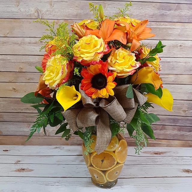 Orange Joy by D'Lily's Flowers - Lovely brights in yellows and oranges, with orange slices in the vase for that fresh display.