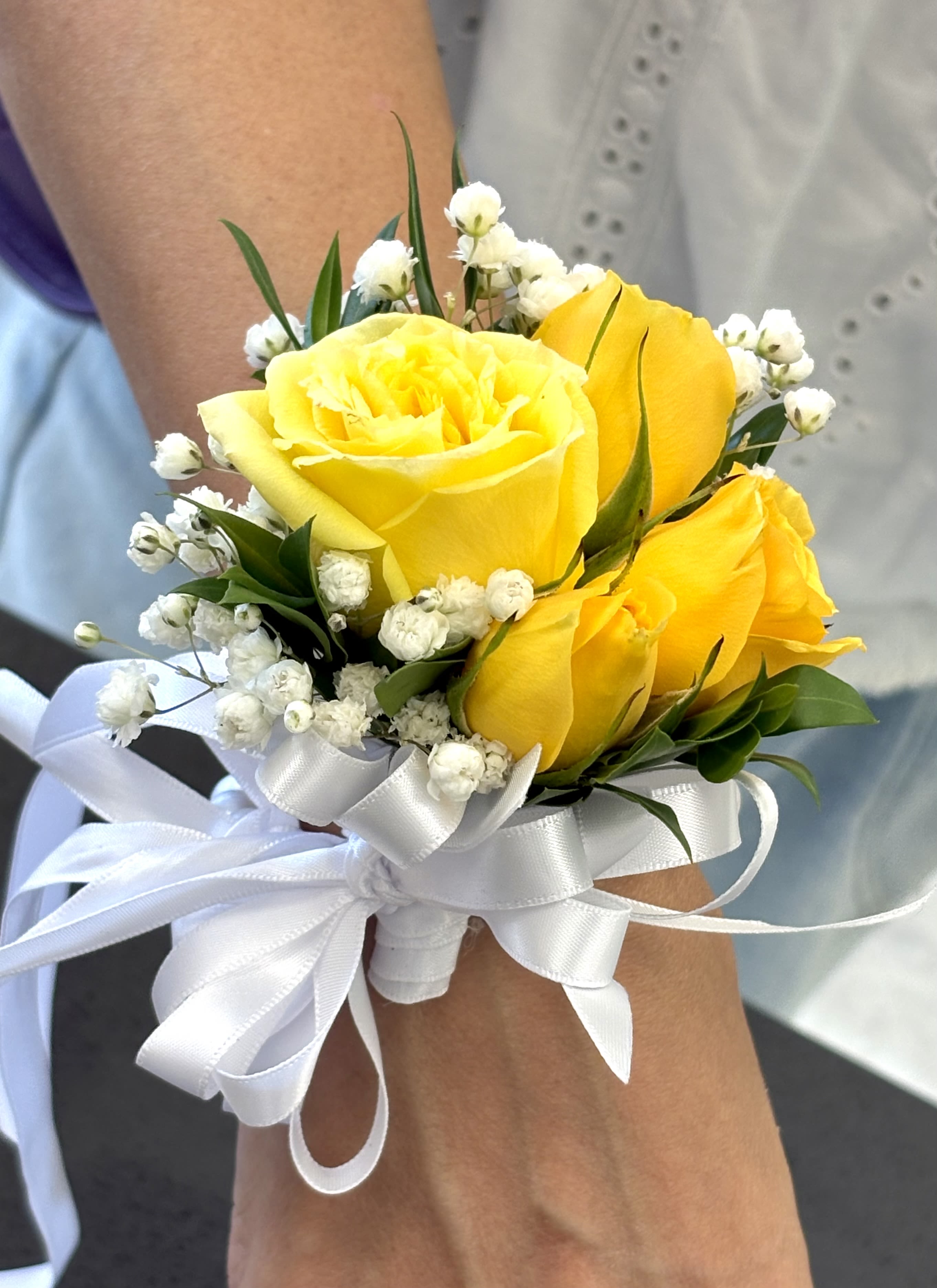 Golden Glow Corsage By VLM Flowers Golden Glow Corsage By VLM Flowers - Bright yellow roses paired with delicate baby’s breath and a crisp white ribbon, radiate cheerful elegance.