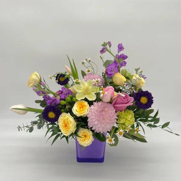 Violet Chemistry - Brighten your Valentine’s Day with this stunning mix of pastel blooms and vibrant pops of color! Featuring roses, tulips, mums, stock, and delicate chamomile daisies, this arrangement is elegantly displayed in a chic purple vase, perfect for celebrating love and joy. Designers may need to implement substitutions, however will follow the general arrangement style and color theme. Standard price point is pictured.