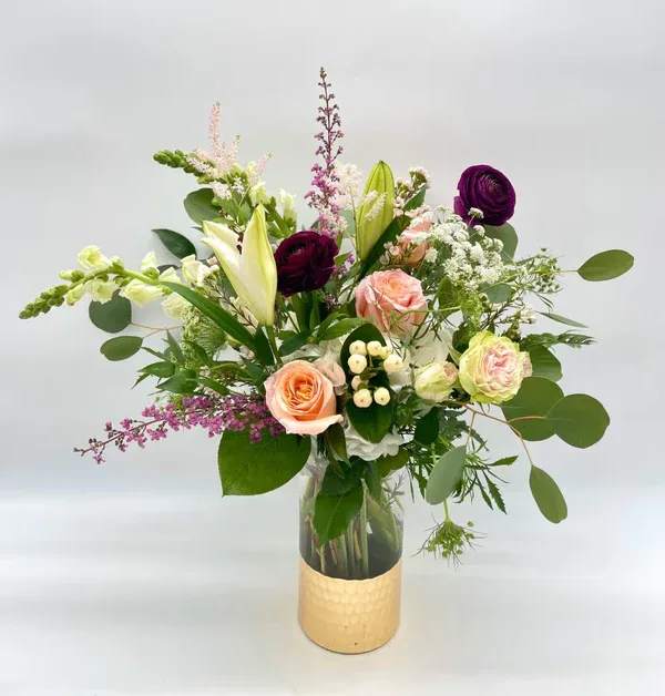 Isn't She Lovely - Sweet and romantic, tall, garden-style arrangement with a mix of soft peaches, pinks and whites with pops of darker reds or burgundy. Designers may need to implement substitutions due to what is available during the season, however will follow the general arrangement style and overall color theme. Standard price point is pictured.  *If gold-dipped vase is unavailable/on backorder, it will be substituted with a clear vase