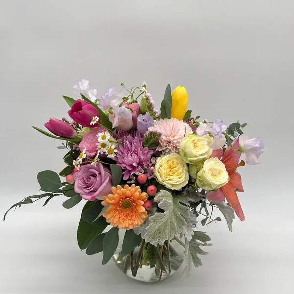 Nana's Garden - Soft pastels and cheerful blooms come together in this whimsical spring arrangement, inspired by the beauty and warmth of Nana’s garden. Bursting with seasonal flowers, it’s a heartfelt reminder of love, nostalgia, and the simple joys of spring. Depending on current inventory, the designer may need to implement substitutions of same value and feel. The standard arrangement is pictured. Deluxe and premium will reflect more flowers and larger size!