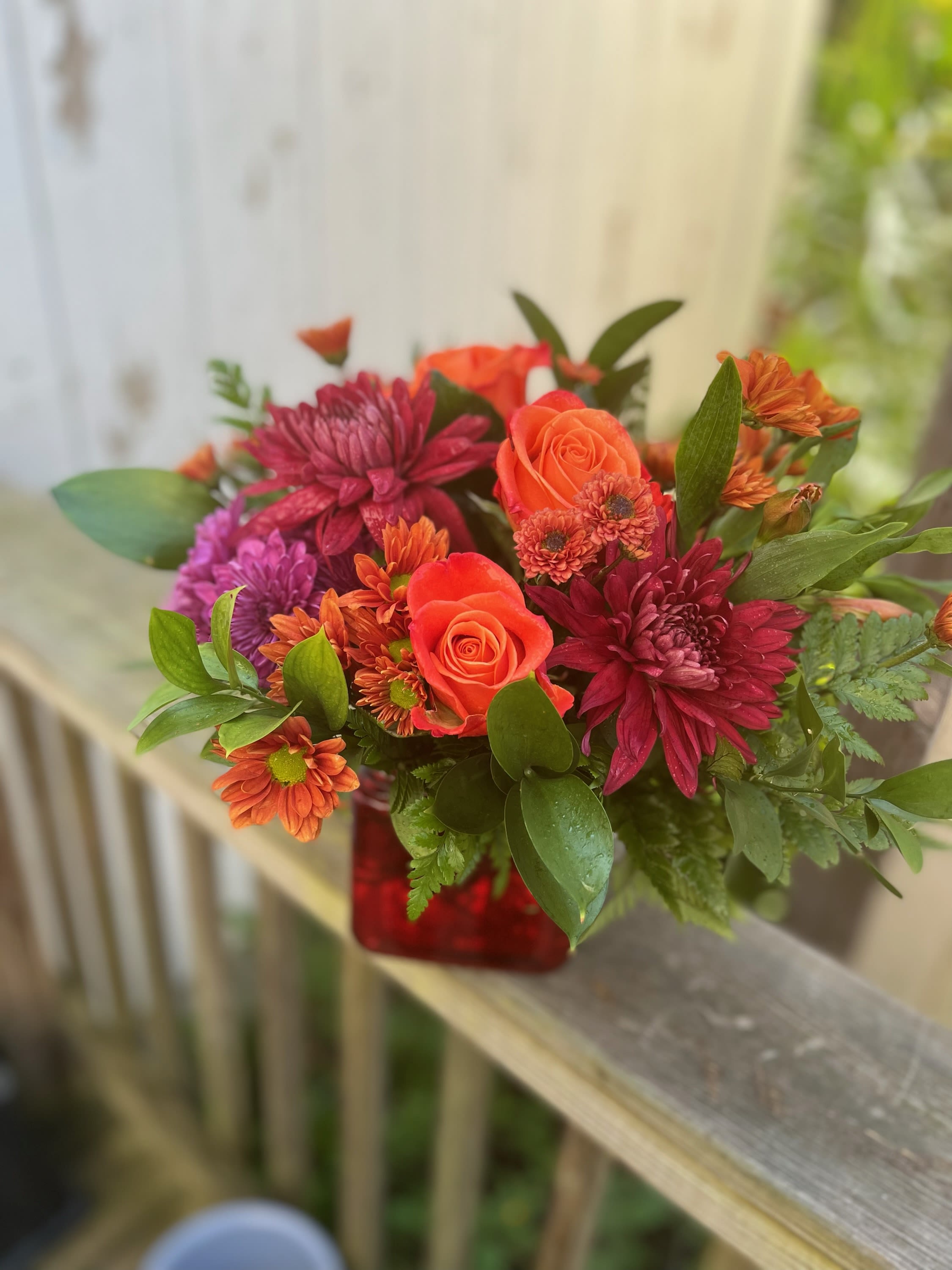 Autumn Glow Bouquet - Orange roses, bronze daisys, rust and purple chrysanthemums arranged in a red cube vase