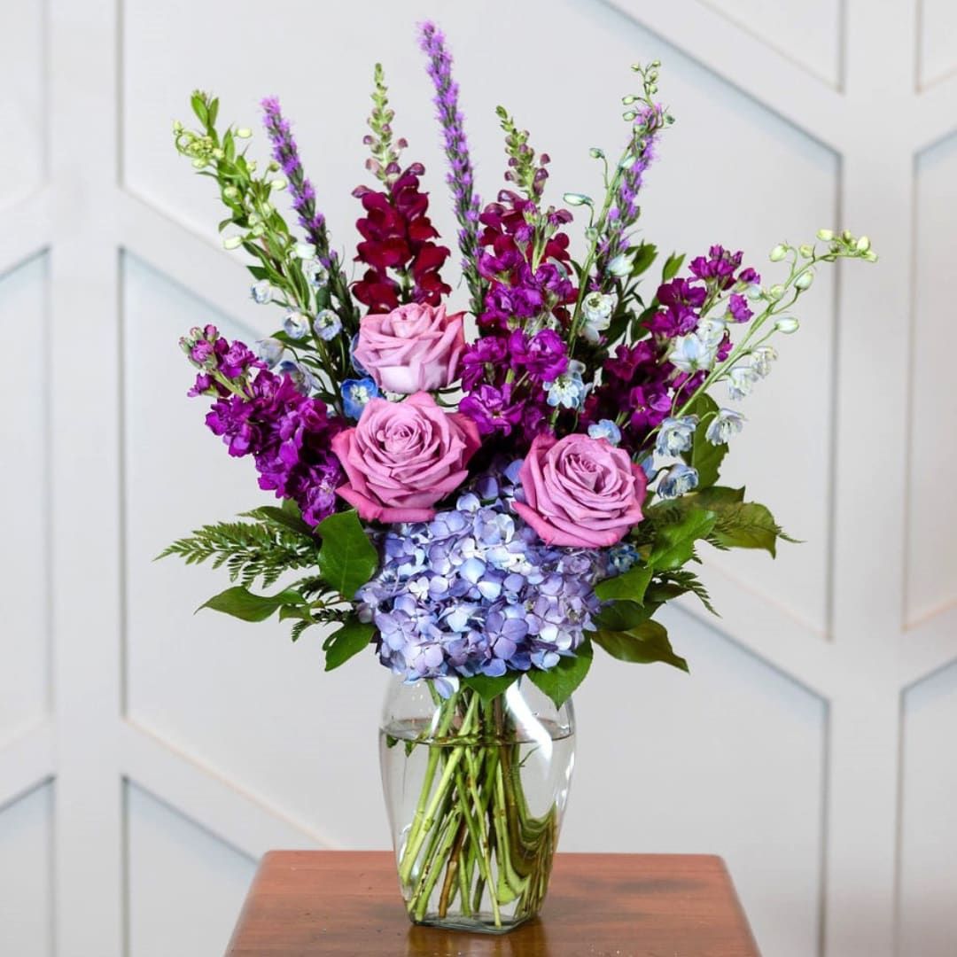 Acclaim - Pink, lavender and blue blossoms classically arranged in a clear vase, making a statement to express your sympathy. 