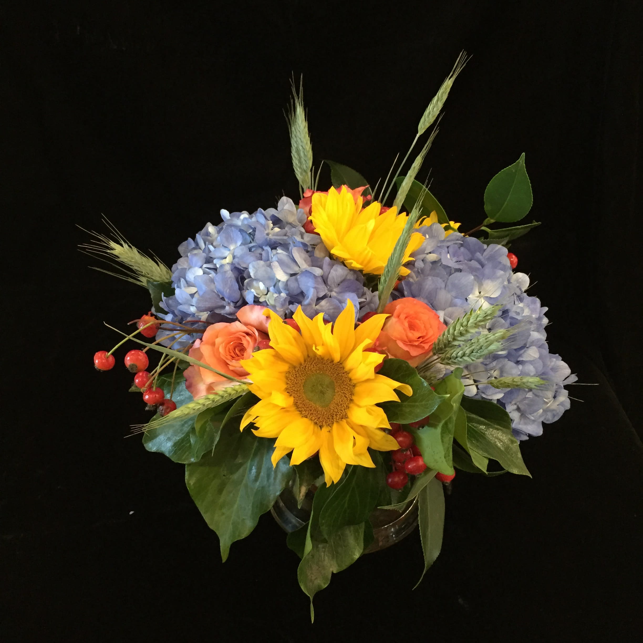 Fall Sunrise - Blue hydrangea, frees spirit roses, sunflowers, rose hips, green wheat. Exact flowers may vary.